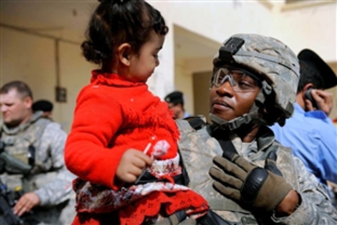 U.S. Army Sgt. 1st Class Waymona T. McIntee befriends a child at a school in Basra, Iraq, Feb. 9, 2009.  McIntee and fellow soldiers of the 21st Military Police Company, 16th Military Police Brigade accompanied members of the Iraqi police during a mission to the school to hand out school supplies.