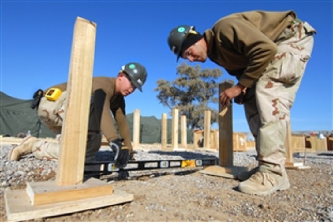U.S. Navy Petty Officer 3rd Class Gary Lamew, assigned to Amphibious Construction Battalion 2, checks the level of a building foundation while making improvements to a patrol base in Mahawil, Iraq, Feb. 4, 2009.