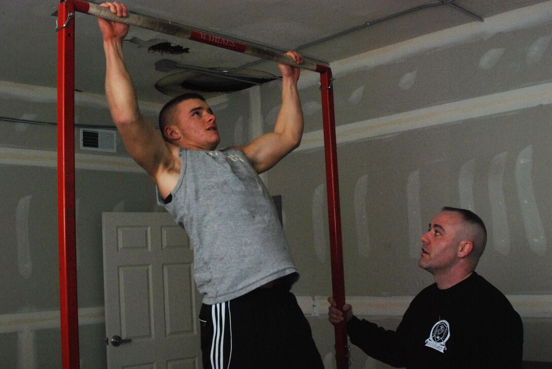 Andrew Dilbeck struggles to do Marine Corps pull-ups for Staff Sgt. George D. Cushing at the Marine Corps Permanent Contact Station in Cuyahoga Falls, Ohio, Feb. 14.  In four months, Cushing has taken eight young men from Cuyahoga Falls and permanently affected their lives in a positive way. Dilbeck is a senior at Manchester High School and Cushing is the recruiter for Cuyahoga Falls, Recruiting Sub-Station Akron, Recruiting Station Cleveland.