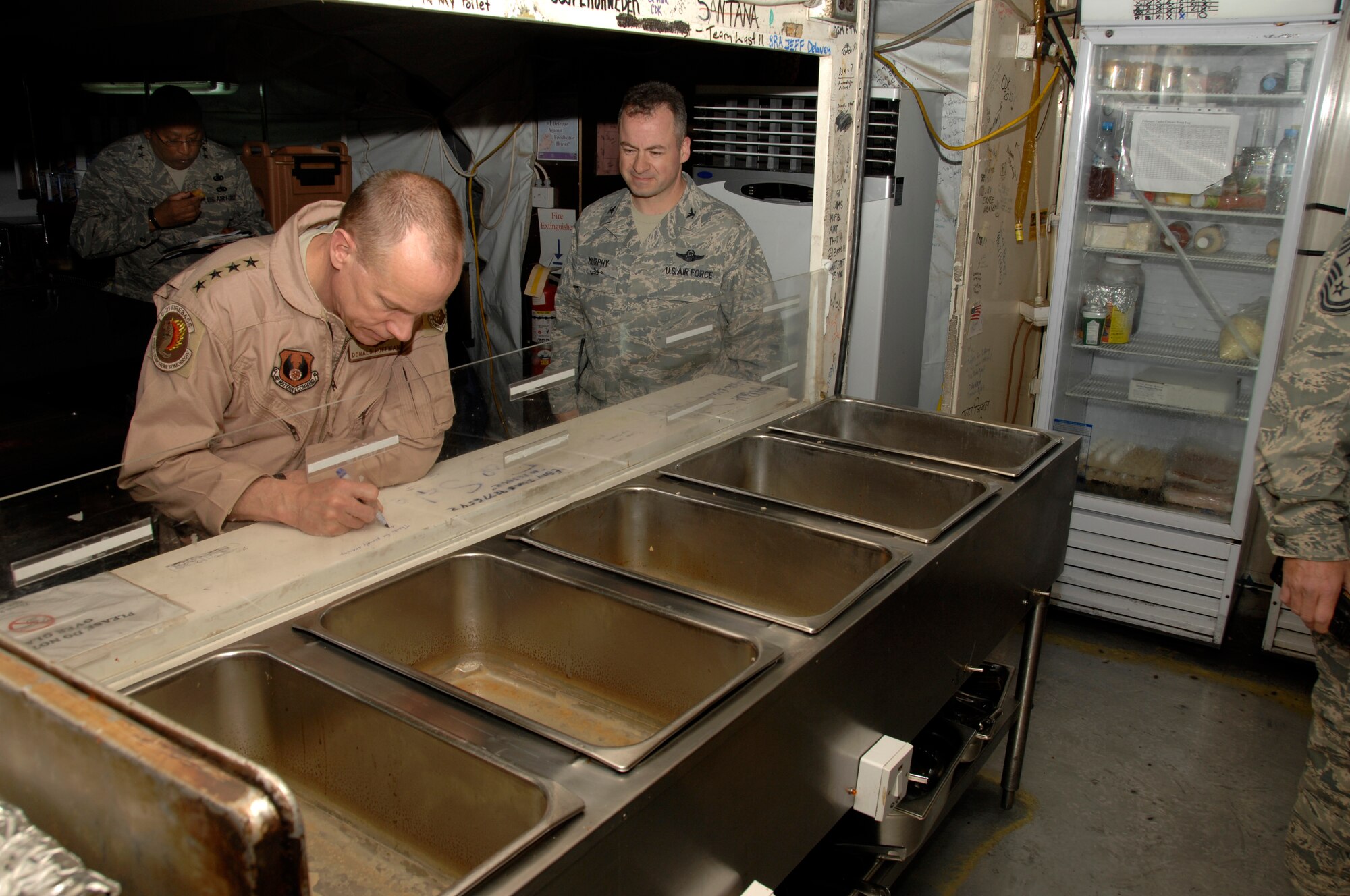 SOUTHWEST ASIA - Gen. Donald J. Hoffman, Air Force Material Command, commander, signs the food service line at Roy's Diner, one of the last remaining Air Force tent-style dining facilities in the area of responsibility, Feb 12. General Hoffman visited Airmen here to learn more about the mission of the 380th Air Expeditionary Wing and challenges the wing has overcome to consistently fly the air tasking order. Gen. General Hoffman is touring the AOR to see each bases capability. (U.S. Air Force photo by Staff Sgt. Mike Andriacco) (Released)