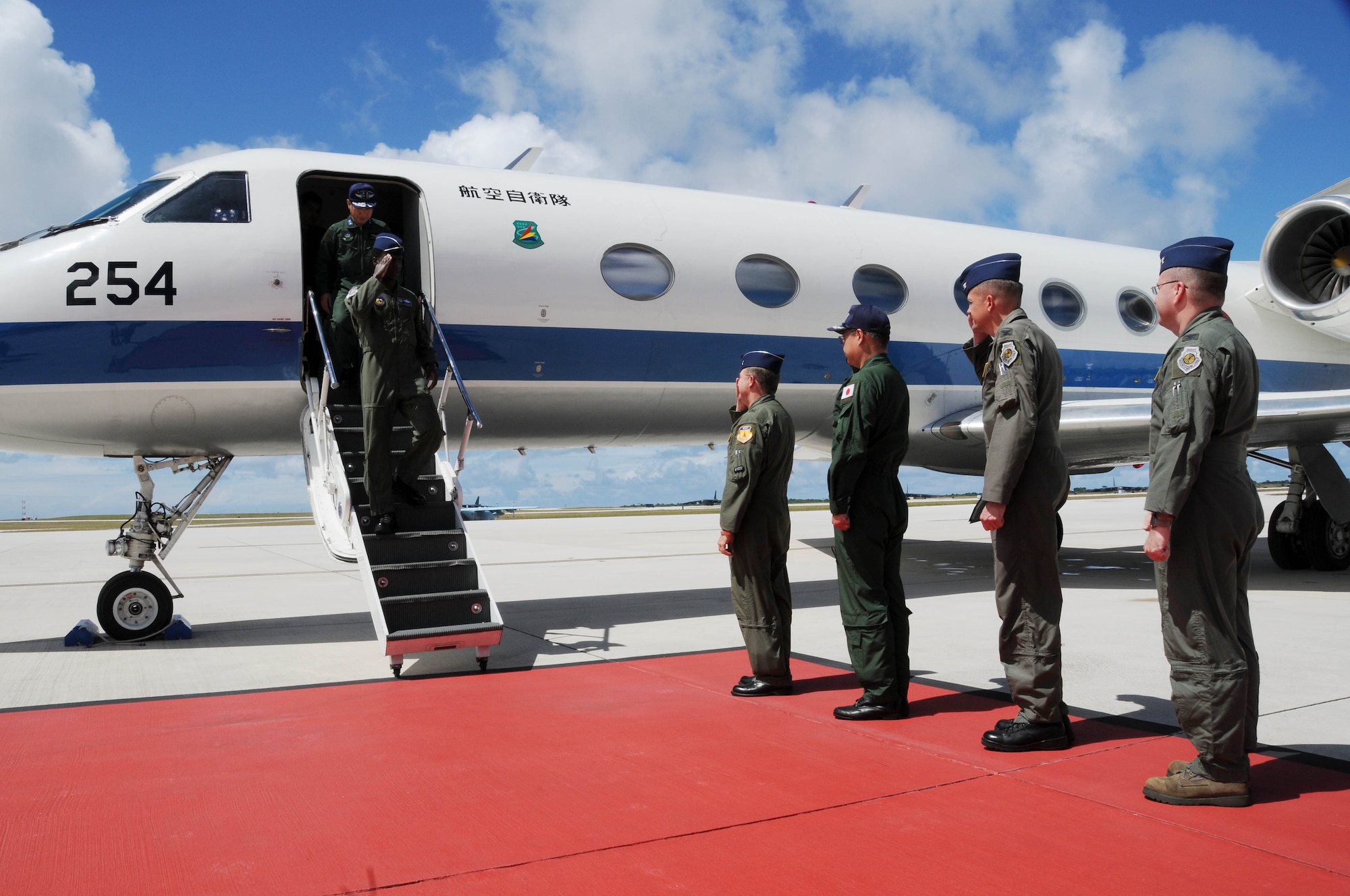 ANDERSEN AIR FORCE BASE, Guam - Brig. Gen. Phil Ruhlman, 36th Wing commander, and a welcoming party salute as Gen. Edward Rice, United States Forces Japan commander, and Maj. Gen. Hideo Wakabayashi, Japan Air Self Defense Force 3rd Air Wing commander, descend from an aircraft here Feb. 12 for a site visit of Andersen. (U.S. Air Force photo by Senior Airman Nichelle Griffiths)