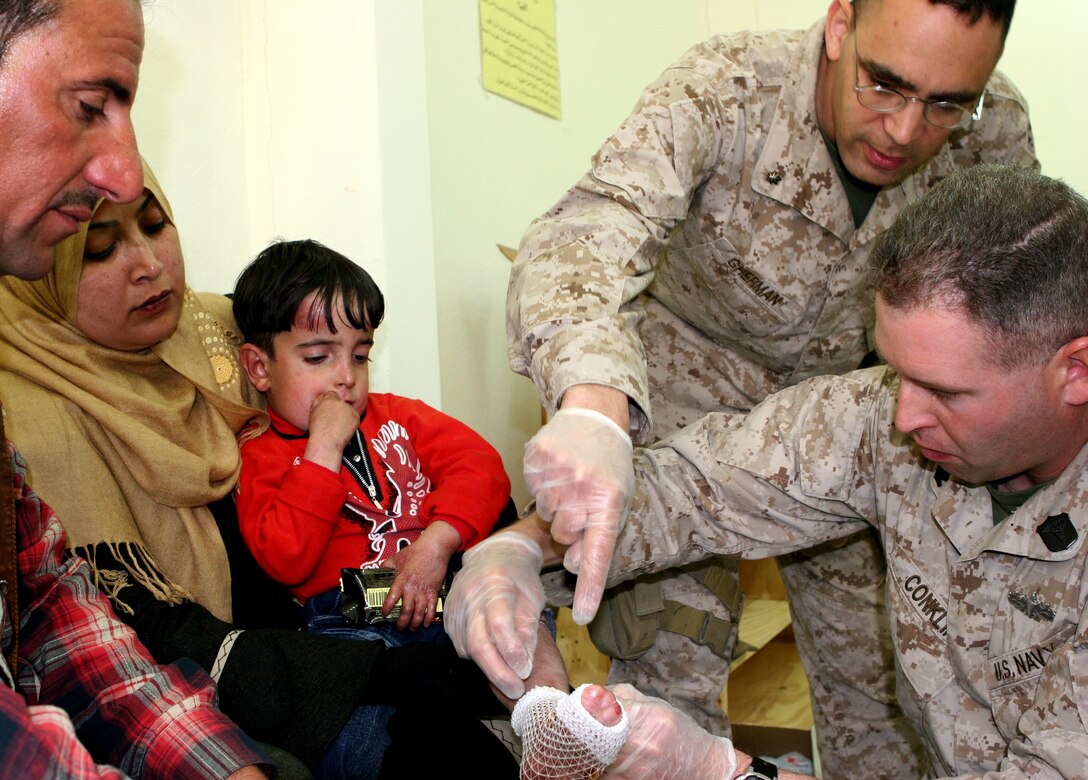 Cmdr. Robert Gherman, battalion surgeon for 2nd Battalion, 25th Marines (top right) and his corpsman, Petty Officer 2nd Class Tad Conklin, explain to the parents of a young Iraqi boy how to properly use medical supplies donated by the University of Cincinnati. Their 5-year-old son, Abdulrahman, is diagnosed with congenital epidermolysis bullosa, a rare skin condition that produces painful sores and blisters and affects one in 5 million people.  The family was inside the Camp Mejid clinic Feb. 16, 2009, where corpsmen and doctors from MNF-W and the Iraqi army delivered medical supplies and instructions on how to provide long-term care to help ease the boy's suffering.