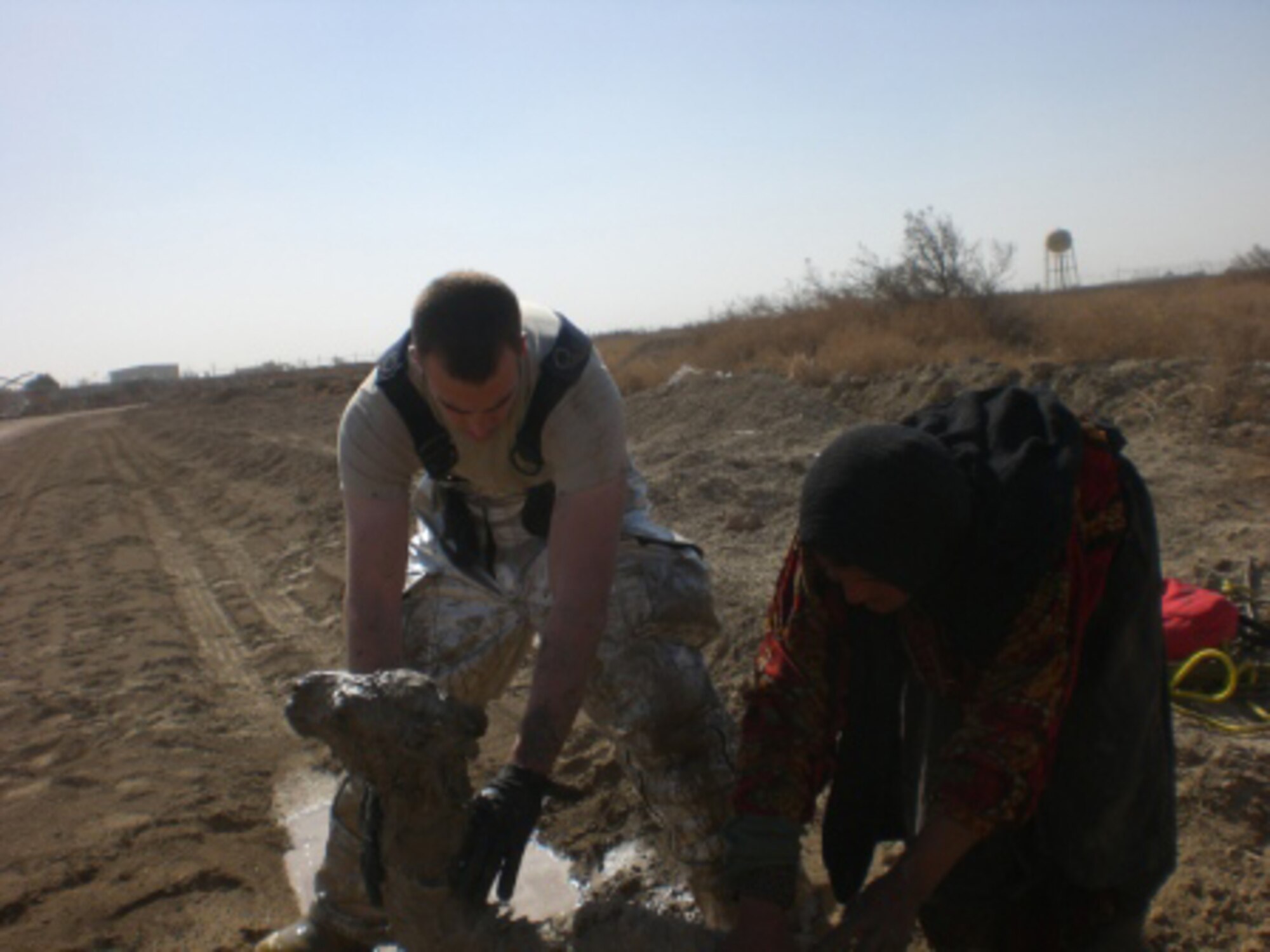 ALI BASE, Iraq -- Staff Sgt. Bryan Senecal and an Afghan woman wash off the baby camel after being trapped at the bottom of a manhole. Sergeant Senecal is a deployed member of the 3rd Civil Engineer Squadron. (U.S. Air Force photo)