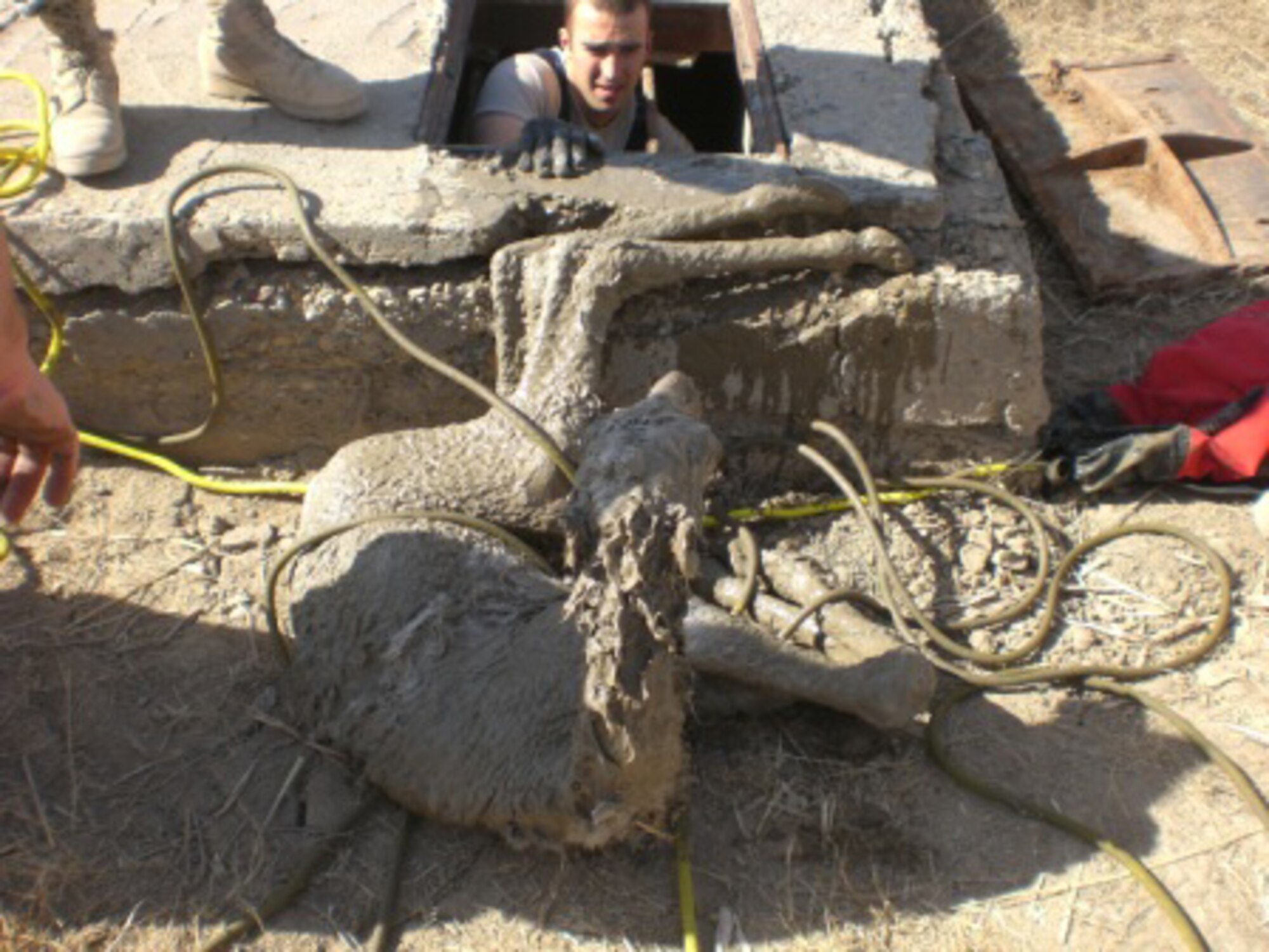 ALI BASE, Iraq -- Staff Sgt. Bryan Senecal, 407th Expeditionary Civil Engineer Squadron Fire and Rescue Services crew chief, climbs out of a manhole after rescuing a baby camel trapped at the bottom. Sergeant Senecal is a deployed member of the 3rd Civil Engineer Squadron. (U.S. Air Force photo)