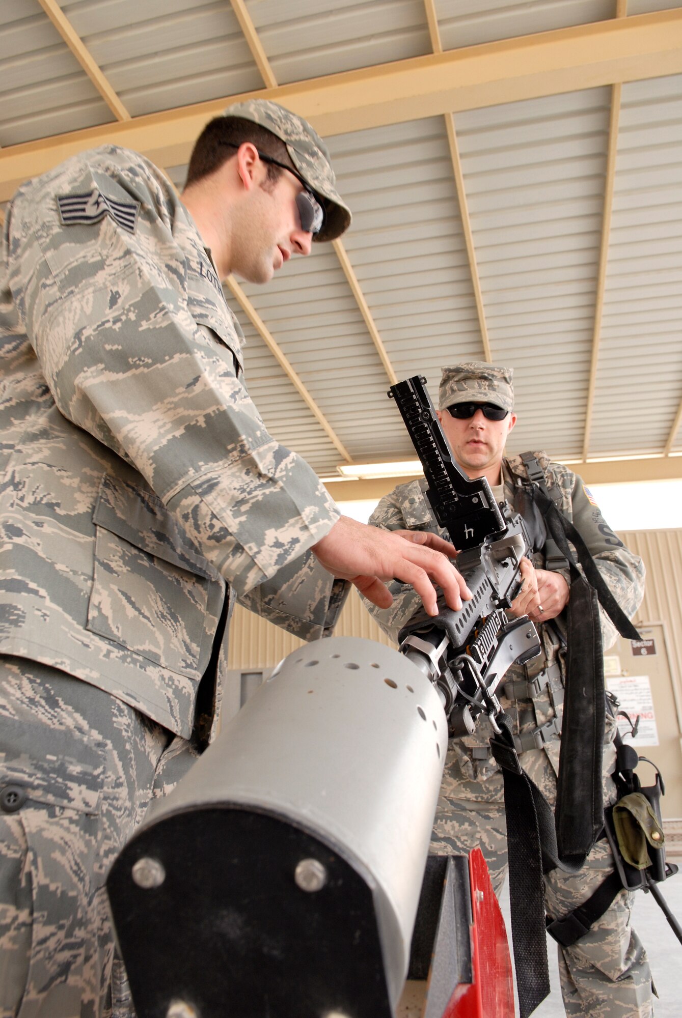 Staff Sergeant Art Lothrop, 379th Expeditionary Security Forces Squadron (ESFS) Combat Arms Training Maintenance (CATM) NCOIC, and Staff Sergeant Nick Wells, 379th ESFS CATM Assistant NCOIC, demonstrate proper clearing procedures for the 240B machine gun, Feb. 15, 2009, at an undisclosed location in Southwest Asia.  Team members from CATM, issue, inspect, and maintain weapons held in the armory for the base.  Staff Sgt. Lothrop hails from Colfax, Wash. and is deployed from Tyndall Air Force Base, Fla.  Staff Sgt. Wells hails from Metropolis, Ill. and is deployed from Vogelweh Air Base, Germany.  Both are deployed in support of Operation Iraqi and Enduring Freedom and Combined Joint Task Force - Horn of Africa.  (U.S. Air Force Photo by Airman 1st Class Andrew Satran/Released)