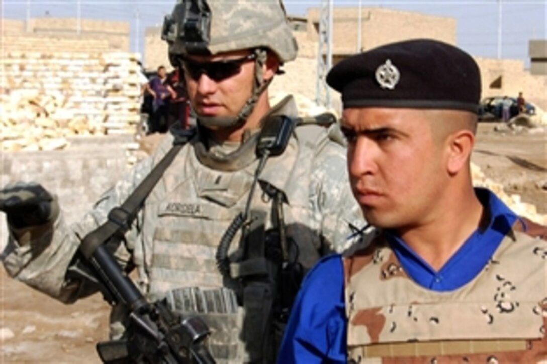 U.S. Army 1st. Lt. Joshua Kordela, left,  looks on with an Iraqi policeman during an operation to rid the Adhamiyah district of eastern Baghdad of weapon caches Feb. 13, 2009. Kordela is a platoon leader with the 25th Infantry Division's 1st Battalion, 27th Infantry Regiment, 2nd Stryker Brigade Combat Team.