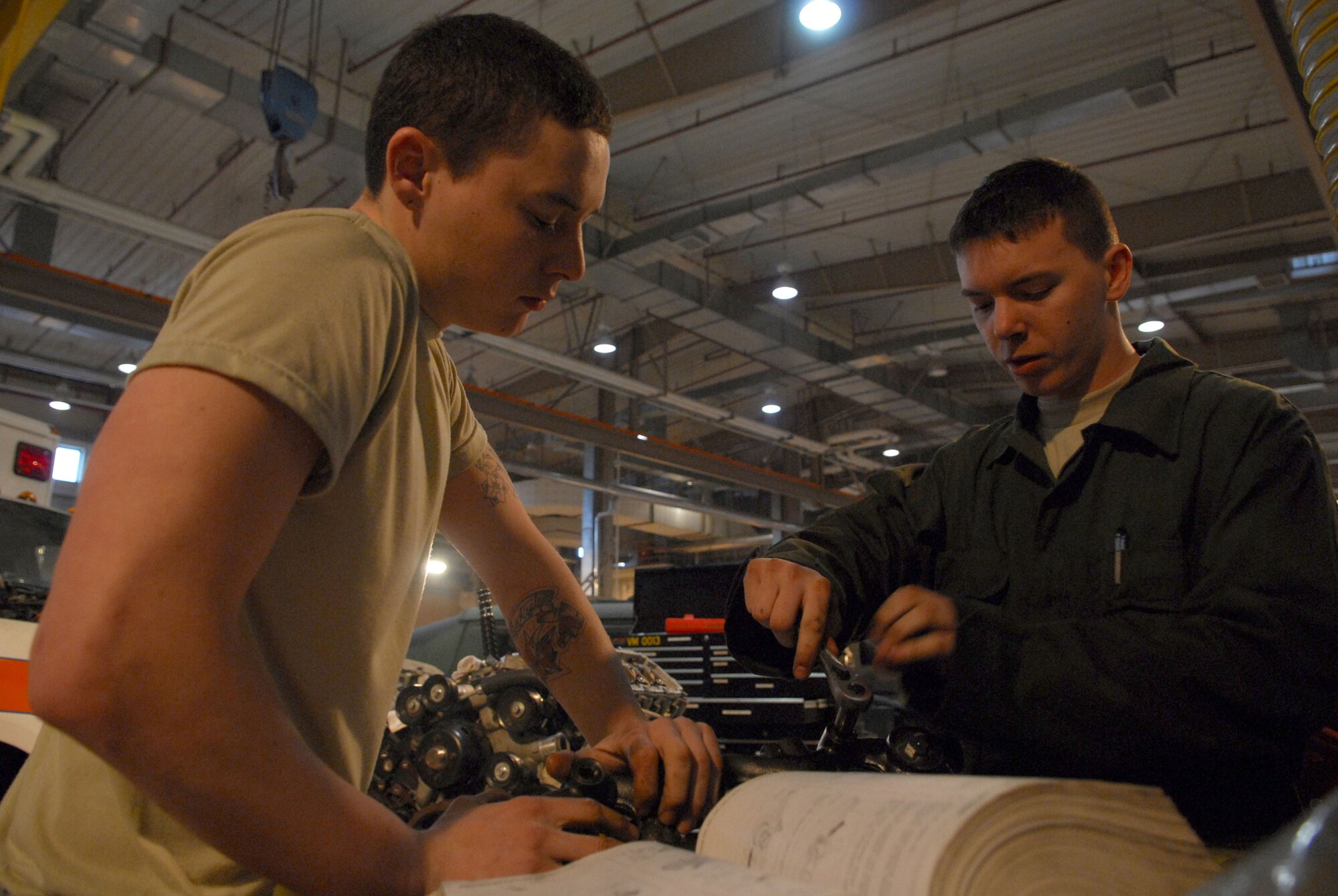 Senior Airmen Casey Van Veckhoven and Jeff Maurer review a technical manual on how to properly torque a crankcase-to-head at Osan AB Republic of Korea Feb 3. Both Airmen Casey and Van Veckhoven are vehicle mechanics assigned to the 51st Logistics Readiness Squadron. (U.S. Air Force photo/Senior Airman Christopher Boitz)