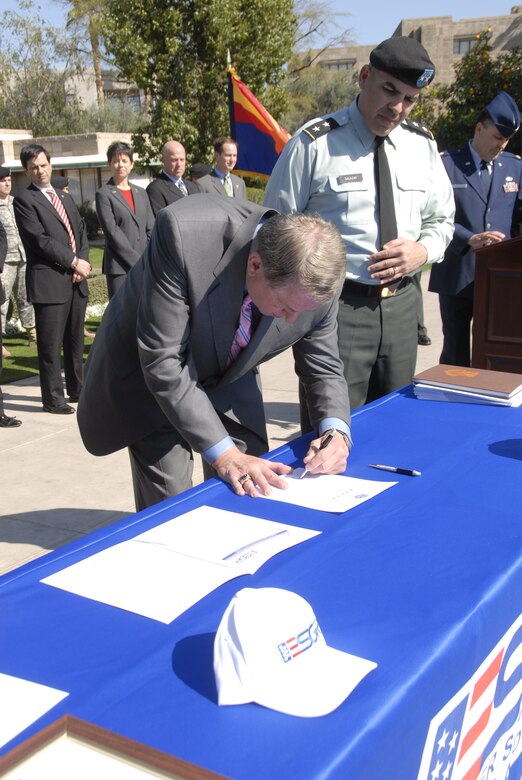 Arizona sports icon Jerry Colangelo, left, signs a Statement of Support for the Employer Support of Guard and Reserve (ESGR) program as Major General Hugo Salazar, The Adjutant General of Arizona, looks on. Other dignitaries present included Phoenix Mayor Phil Gordon, background, far left. (Arizona National Guard photo by Army Sgt. Ed Balaban)