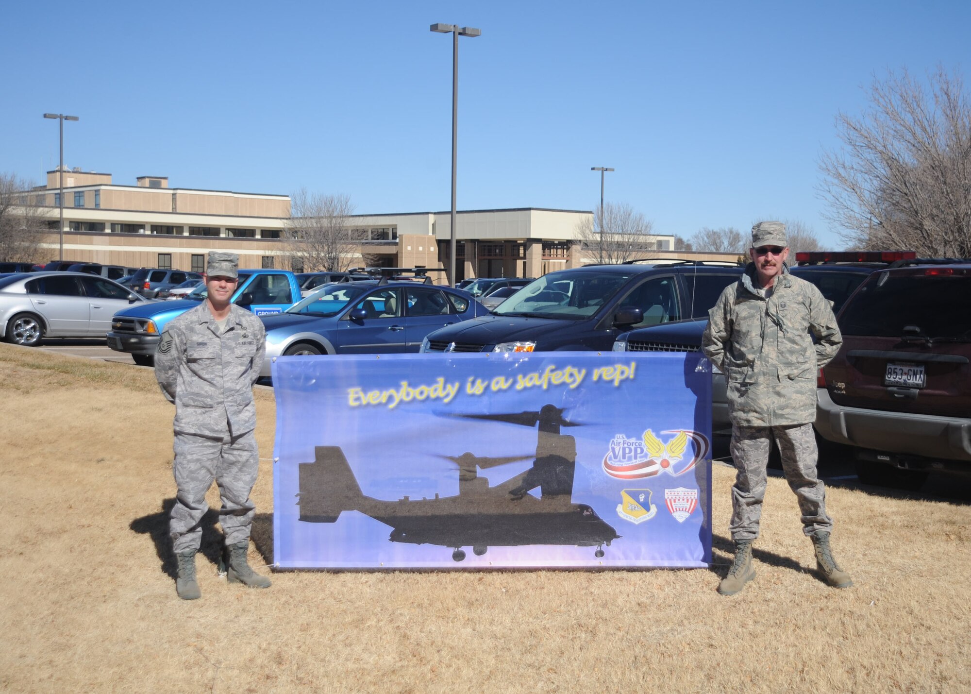 CANNON AIR FORCE BASE, N.M.-- (left) Master Sgt. Charles Siroin and Master Sgt. William Keely, 27th Special Operations Wing Safety Office, stand beside their Voluntary Protection Program banner outside the medical clinc. There are banners around base notifying base personnel about VPP and are located at the medical clinic, Portales gate, by the BX and on the fence by Civil Engineer electrical. (U.S. Air Force photo/Airman 1st Class Maynelinne De La Cruz)