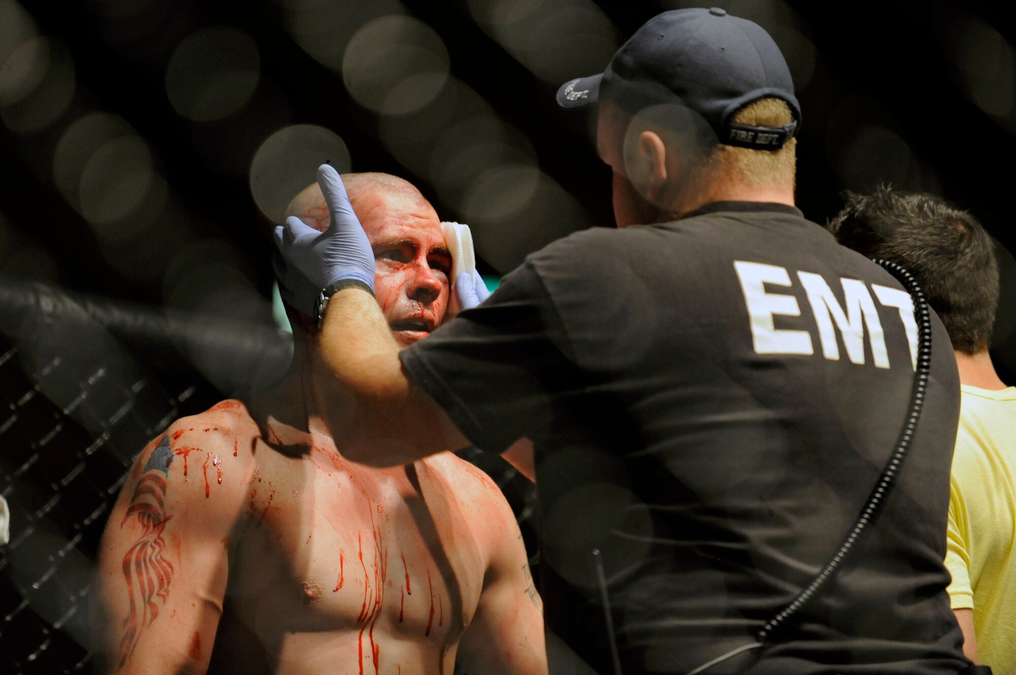 (Left) Staff Sgt. Derek Winters, 28th Maintenance Squadron avionics systems journeyman, is treated by an emergency medical technician during a fight with Travis Parazoo at the Rushmore Plaza Civic Center in Rapid City, S.D., Feb. 13. The match was called a draw after an illegal hit by Parazoo during the amateur competition.  (US Air Force photo/Airman 1st Class Corey Hook)