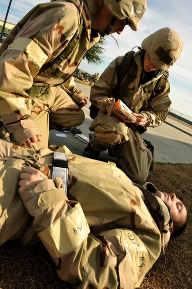 MOODY AIR FORCE BASE, Ga. -- Airman Jared McWilliams and Airman 1st Class Jared Armstrong, both members of the 38th Rescue Squadron, review the Airman’s Manual Self-Aid and Buddy Care procedures while administering assistance to Staff Sgt. David Parker, a 41st Rescue Squadron member, during the Phase II Operational Readiness Exercise Feb. 9-13 here. (U.S. Air Force photo by Senior Airman Schelli Jones)