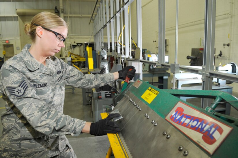 Staff Sgt. Lynn Plemons, 305th Maintenance Squadron Maintenance Fabrication Flight training manager, uses a box and pan brake to bend tabs on a sheet of metal. When the red lever is pushed back, the metal is clamped and secured in place. The yellow area is called the bending leaf and this part moves up to actually bend the metal into shape. Any metal that is too thick for this machine to bend is moved over to the hydraulic brake. (U.S. Air Force photo/Carlos Cintron)