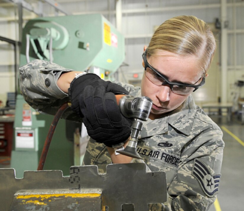 Staff Sgt. Lynn Plemons, 305th Maintenance Squadron Maintenance Fabrication Flight training manager, uses a right angle sanding disk to smooth out the edges on an external power cord receptacle bracket. This prevents the metal from cracking during flight. The primary mission of the sheet metal shop is to ensure structural integrity of KC-10 and C-17 airframes. (U.S. Air Force photo/Carlos Cintron)