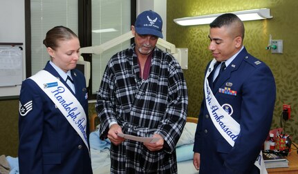 Capt. Carlos Ferrer, 341st Recruiting Squadron, and Staff Sgt. Courtney Linde, 12th Contracting Squadron, both Randolph Ambassadors, deliver hand-made Valentine's Day cards to Michael Krupalla, an Air Force veteran at Audie L. Murphy Memorial Veterans Hospital, on Feb. 13 as part of the annual National Salute to Hospitalized Veterans Program. Col. Jacqueline Van Ovost, 12th FTW commander, and Chief Master Sgt. Max Grindstaff, 12th FTW command chief master sergeant joined the ambassadors in wishing good health to fellow veterans and thanking them for their service. (U.S. Air Force photo by Don Lindsey)