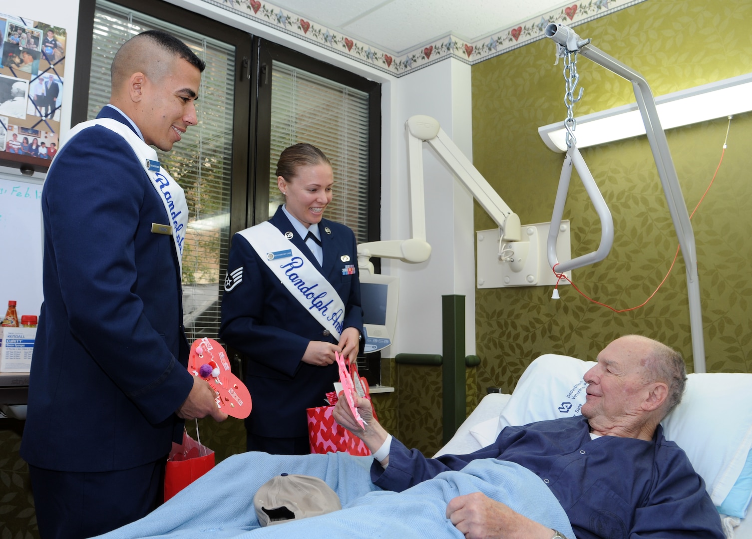 Capt. Carlos Ferrer, 341st Recruiting Squadron, and Staff Sgt. Courtney Linde, 12th Contracting Squadron, both Randolph Ambassadors, deliver hand-made Valentine's Day cards to Thomas Black Jr, a retired Air Force veteran at Audie L. Murphy Memorial Veterans Hospital, on Feb. 13 as part of the annual National Salute to Hospitalized Veterans Program. Col. Jacqueline Van Ovost, 12th FTW commander, and Chief Master Sgt. Max Grindstaff, 12th FTW command chief master sergeant joined the ambassadors in wishing good health to fellow veterans and thanking them for their service. (U.S. Air Force photo by Don Lindsey)