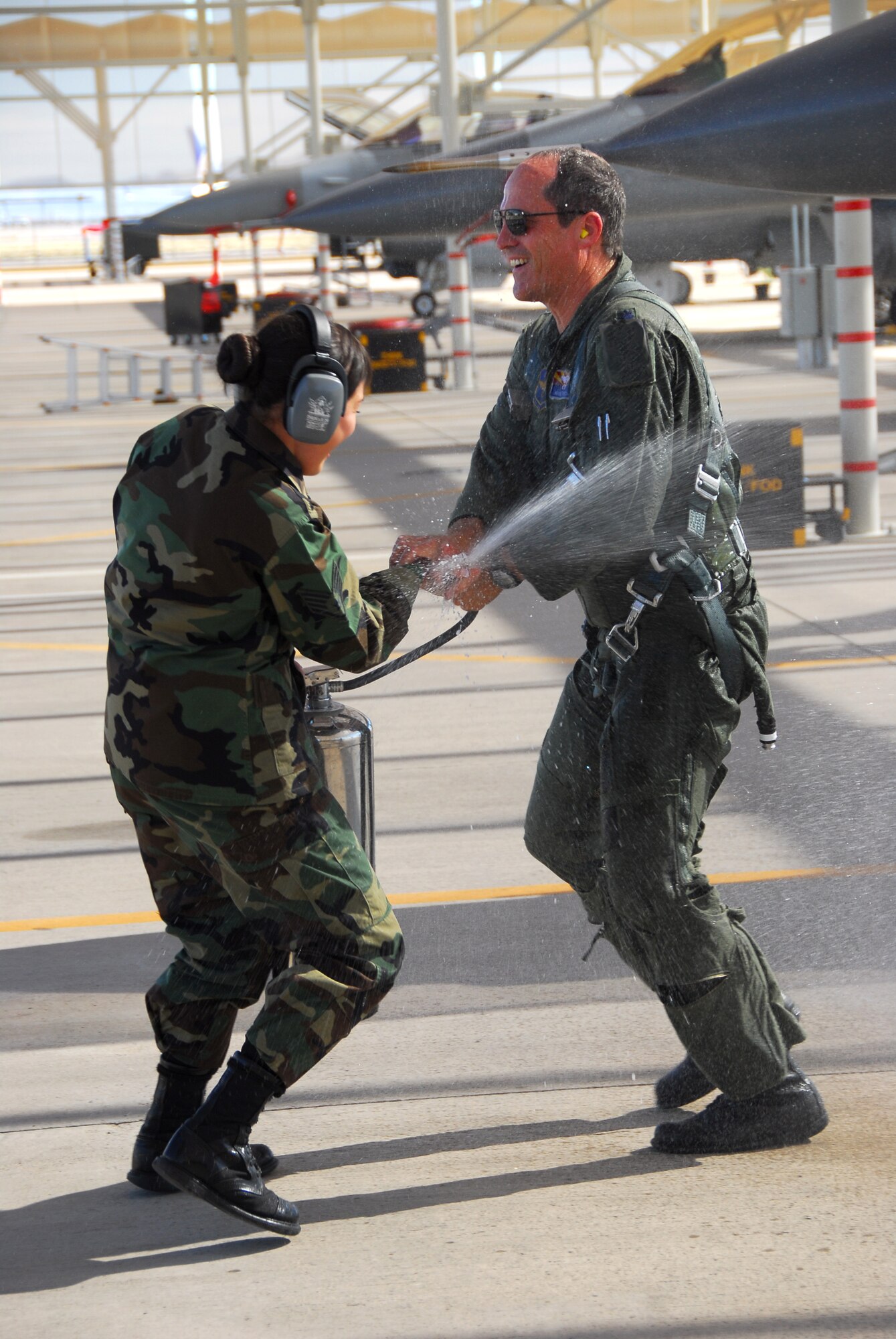 Lt. Col. Bruce Patch, an F-16 pilot, gets hosed down on the flightline by Staff Sgt. Annie Jaramillo after his fini flight here Feb. 12. When Colonel Patch announced his fini flight to friends and co-workers weeks prior, a flood of volunteers came forward for the honor of drenching him. In turn, he raffled the opportunity among wing members at $1 per ticket to benefit the 162nd Fighter Wing Family Readiness Group. The raffle raised more than $100 to benefit Guard families. “I was hoping this raffle would become a tradition among pilots who retire from the 162nd. It’s for a good cause,” said Colonel Patch. He and his wife Tracy will move to Denver, Colo., where he will assume a position as a quality manager with the Veteran’s Administration’s Health Administration Center heading a Lean process. (Air National Guard photo by Master Sgt. Dave Neve)