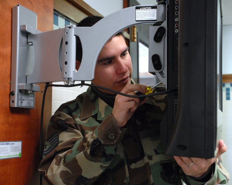 Tech. Sgt. Richard Ortega, 436th Civil Engineer Squadron dorm manager (Dorm 435), installs a T.V. in the laundry room. Dorm managers provide residents with equipment to boost morale, and to help make Airmen feel welcomed and at home. (U.S. Air Force photo/ Airman 1st Class Shen-Chia Chu)