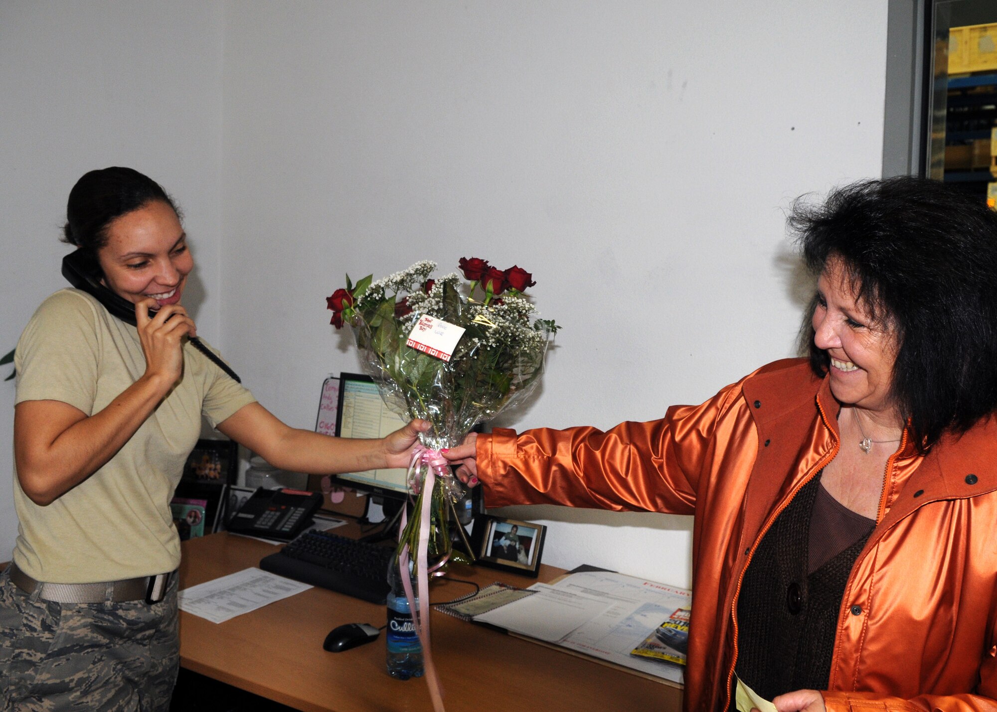 SPANGDAHLEM AIR BASE, Germany -- Staff Sgt. Nickola Swallers, 52nd Logistic Readiness Squadron, receives flowers delivered by Joanne Fiozen, Spangdahlem Flower Shop owner, as she speaks to her husband on the phone. The Spangdahlem Flower Shop employees worked through the night to make sure flower orders were ready for delivery on Valentine’s Day.  (U.S. Air Force photo by Airman 1st Class Staci Miller)