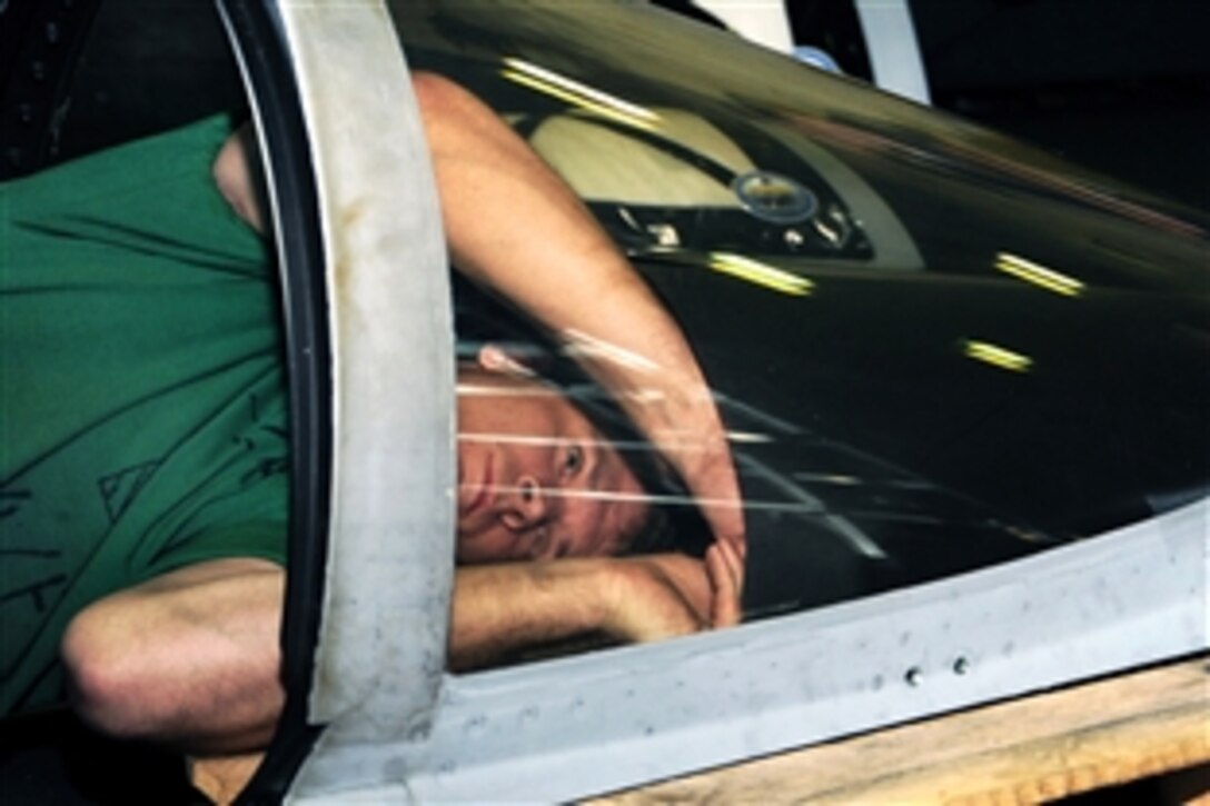 U.S. Navy Petty Officer 3rd Class Jonathon Whitman, an aviation mechanic, removes parts of a windscreen from an F/A-18F Super Hornet aboard USS Theodore Roosevelt under way in the Gulf of Oman, Feb. 13, 2009.