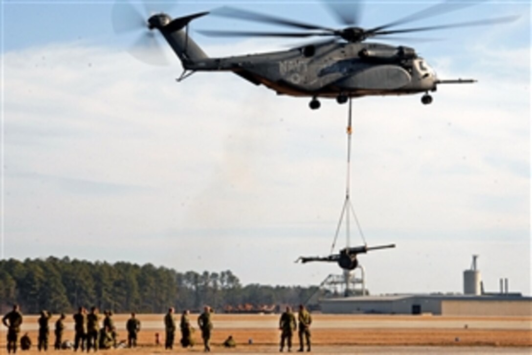 U.S and Canadian soldiers watch as a Navy MH-53E Sea Dragon helicopter carries a sling-loaded howitzer during training for Exercise Southbound Trooper IX on Blackstone Army Airfield, Fort Pickett, Va., Feb. 14, 2009.