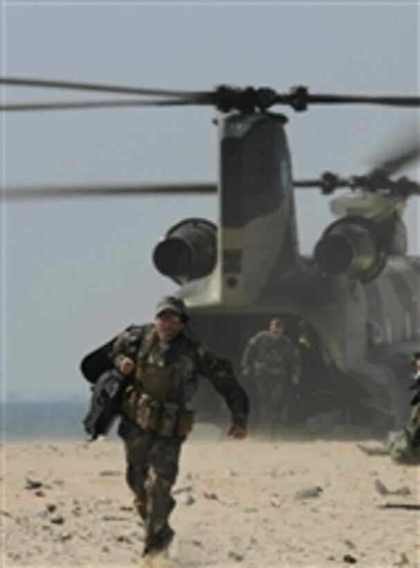 U.S. Air Force Capt. Harmon, a combat rescue officer with the 31st Rescue Squadron, runs to his team after exiting a CH-47 Chinook helicopter on a beach off the coast of Okinawa, Japan, during exercise Cope Angel 09-1 on Feb. 12, 2009.  Cope Angel is a joint rescue exercise between service members from the U.S. Air Force and the Japanese Air Self Defense Force.  