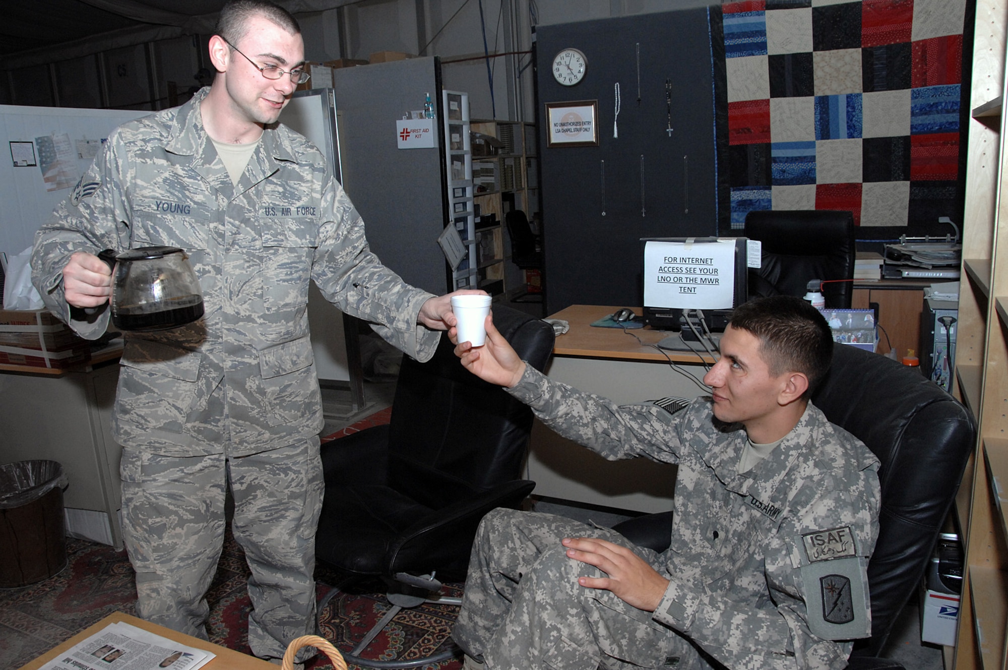 Senior Airman Alexander Young, a chaplain assistant in the 586th Air Expeditionary Group's Gateway Chapel Section, offers a cup of coffee to a Soldier transiting through the Army's Life Support Area Feb. 12 at an air base in Southwest Asia. Airmen in the Gateway Chapel Section made hospitality a keystone of their ministry which is tasked primarily with counseling troops on emergency leave. (U.S. Air Force photo/Senior Airman Courtney Richardson)