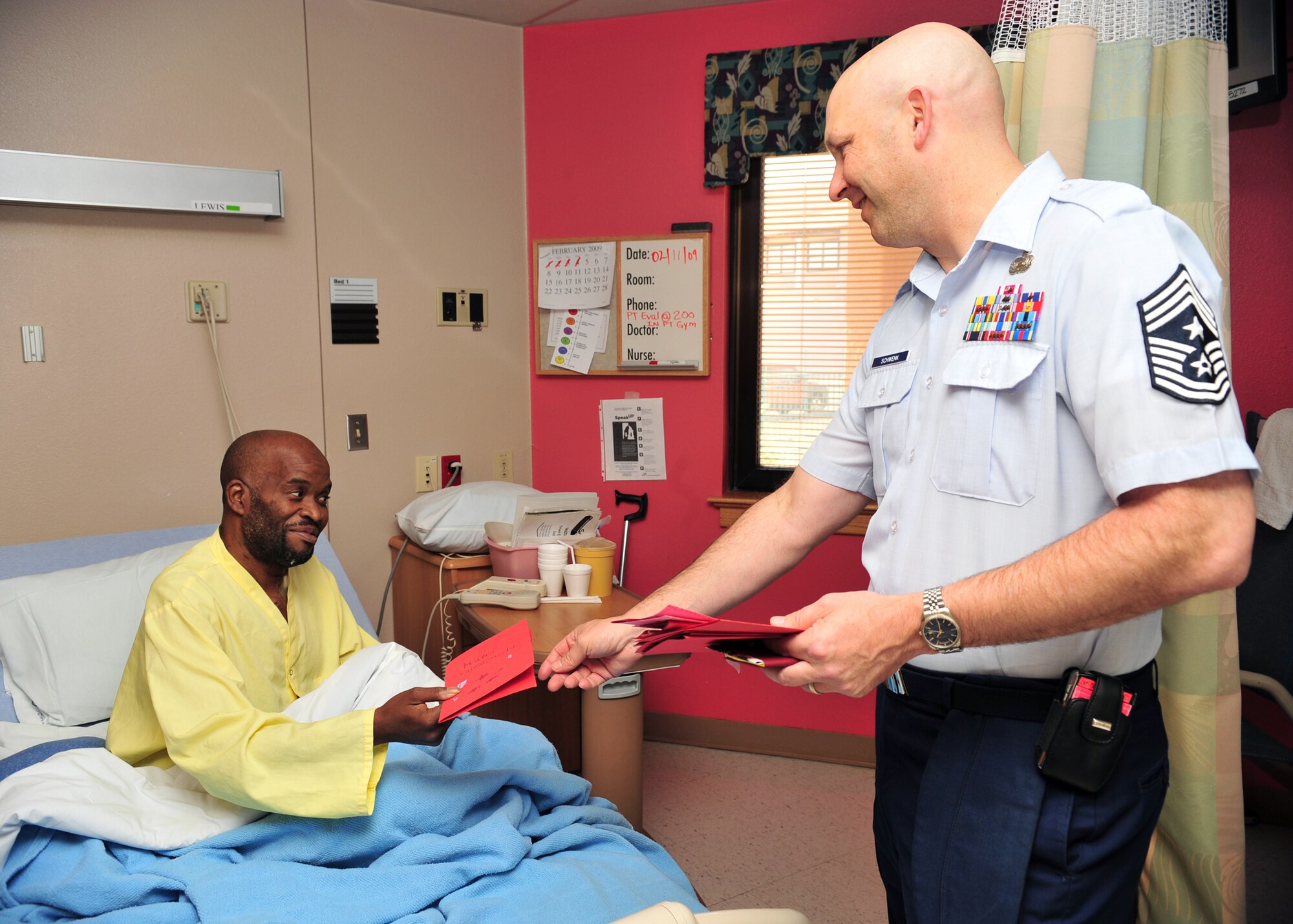 Chief Master Sgt. Thomas Schwenk, 355th Figther Wing Command Chief, greets patient Gerald Lewis with a Valentine's Day card during the the 34th Annual National Salute to hospitalized Veterans at the VA hospital in Tucson, Feb. 11. (U.S. Air Force photo/Senior Airman Noah R. Johnson)