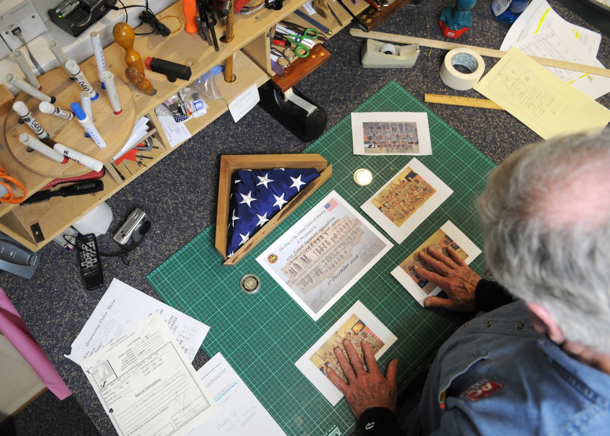 Jim Coleman, a framing and woodworking specialist, groups photos for ideas of a shadow box at the Arts and Crafts Center Jan. 28, 2009, at RAF Mildenhall, England. Mr. Coleman is able to create a wide variety of custom pieces for almost any occasion. For more information about hours of operation and pricing, contact the Arts and Crafts Center in Building 422 at DSN 238-3709. (U.S. Air Force photo by Staff Sgt. Jerry Fleshman)