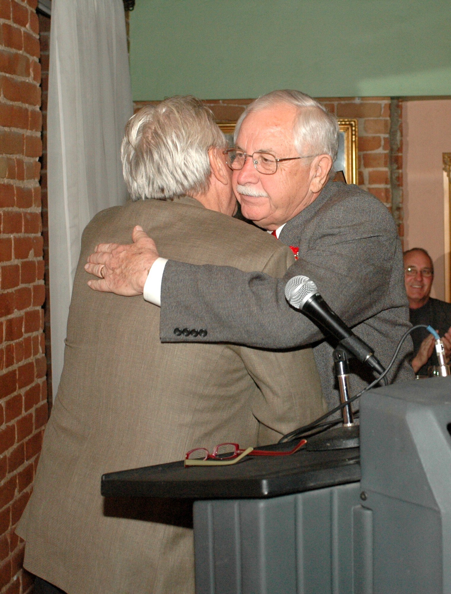 Bill Valenzuela, right, embraces friend and colleague Jack Camper at the banquet held in Valenzuelas honor. Camper presented a copper plaque from Tucson Mayor Robert Walkup. (Air National Guard photo by Capt. Gabe Johnson)