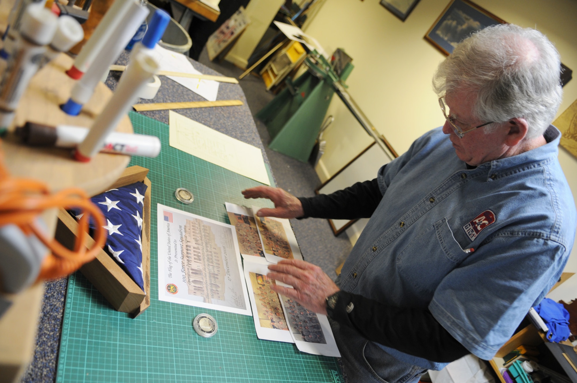 Jim Coleman, a framing and woodworking specialist, groups photos for ideas of a shadow box at the Arts and Crafts Center Jan. 28, 2009, at RAF Mildenhall, England. Mr. Coleman is able to create a wide variety of custom pieces for almost any occasion. For more information about hours of operation and pricing, please contact the Arts and Crafts Center in building 422 at DSN 238-3709. (U.S. Air Force photo by Staff Sgt. Jerry Fleshman)