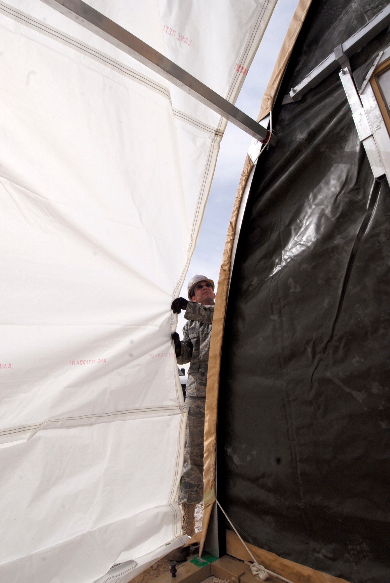 Airman 1st Class Michael Babcock, a 379th Expeditionary Civil Engineer Squadron Structural Journeyman, insures the skin for the California Medium Shelter System (CAMSS) does not tear over the archway being covered, Feb. 17, 2009, at an undisclosed location in Southwest Asia.  Airman 1st Class Babcock hails from Sheridan, Mich. and is deployed from Dover Air Force Base, Del. in support of Operations Iraqi and Enduring Freedom and Combined Joint Task Force - Horn of Africa.  (U.S. Air Force photo/Airman 1st Class Andrew Satran/released)