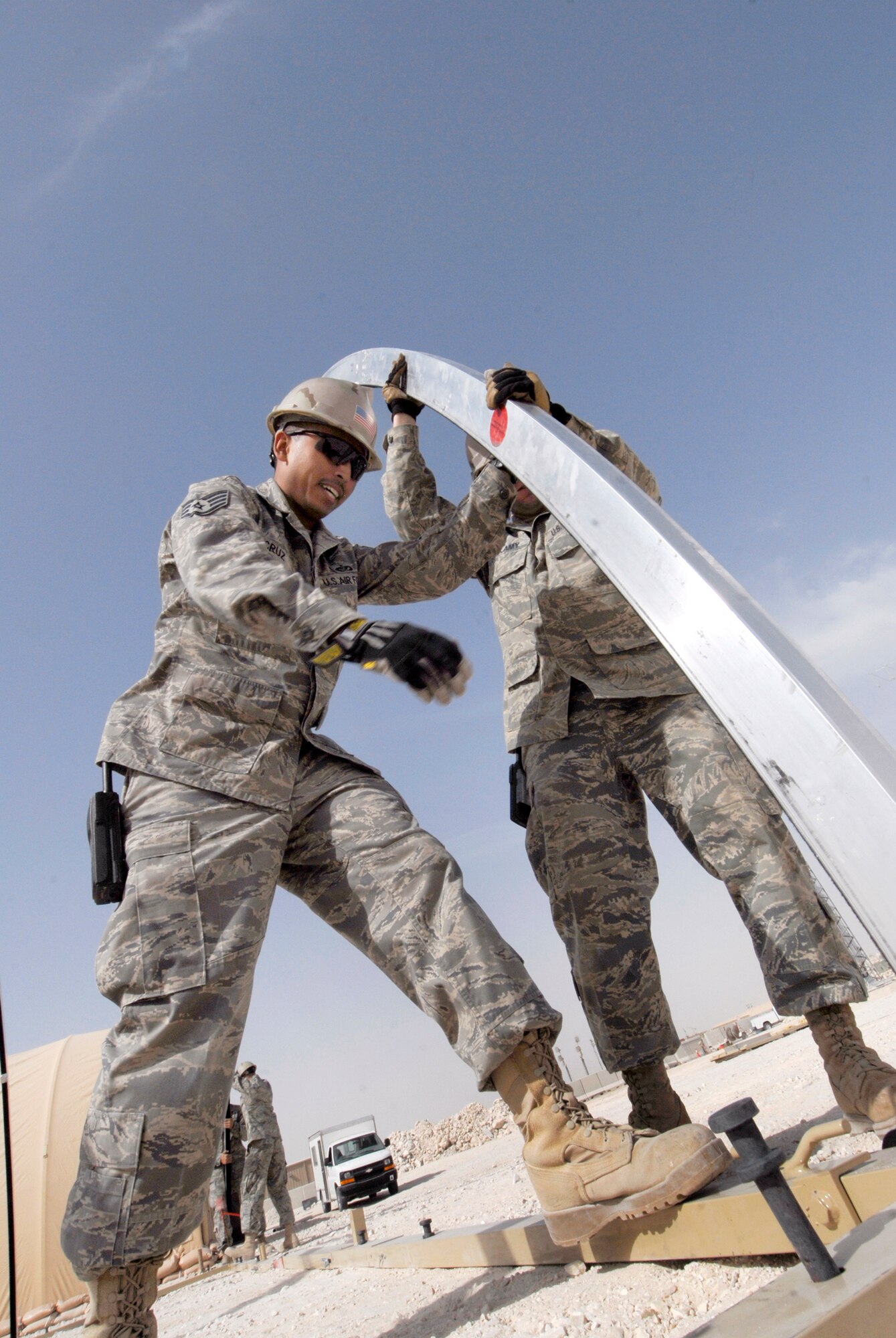 Staff Sergeant Matthew Cruz and Staff Sergeant Evan Bellamy, 379th Expeditionary Civil Engineer Squadron Structural Craftsmen, raise an arch component to finish the skeleton of a California Medium Shelter System (CAMSS) which will be used to house Airmen, Feb. 17, 2009, at an undisclosed location in Southwest Asia.  Staff Sgt. Cruz hails from Tacoma, Wash. and is deployed from Pope Air Force Base, N.C.  Staff Sgt. Bellamy hails from Sullivan County, N.Y. and is deployed from Dover Air Force Base, Del.  Both are deployed in support of Operations Iraqi and Enduring Freedom and Combined Joint Task Force - Horn of Africa.  (U.S. Air Force photo/Airman 1st Class Andrew Satran/released)   