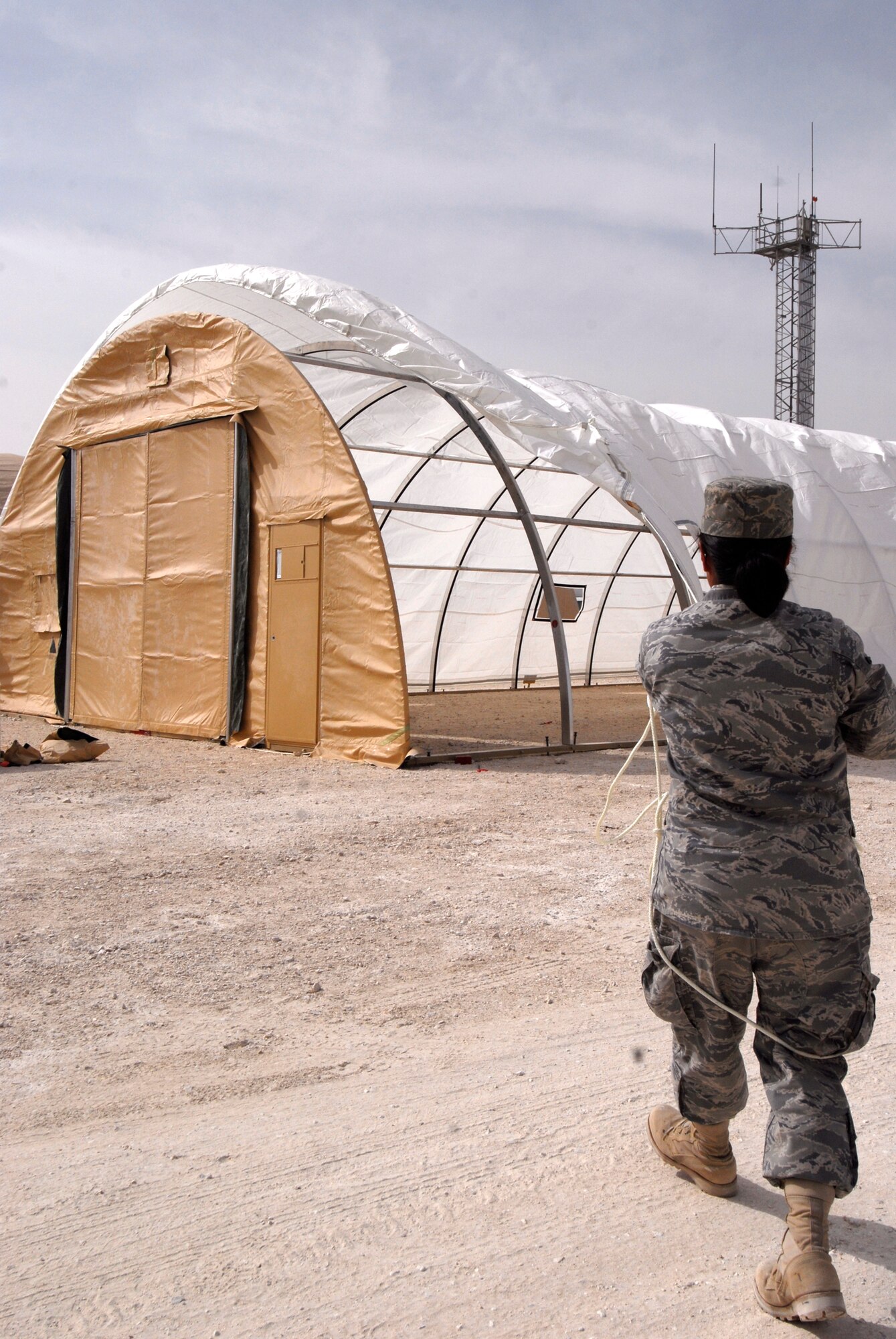 Airman 1st Class Ingrid Tamayo, a 379th Expeditionary Civil Engineer Squadron Structural Apprentice, Keeps tension on  the skin going over the arches of a California Medium Shelter System (CAMSS) used to house Airmen, Feb. 17, 2009, at an undisclosed location in Southwest Asia.  Airman 1st Class Tamayo hails from Los Angeles, Calif. and is deployed from Travis Air Force Base, Calif. in support of Operations Iraqi and Enduring Freedom and Combined Joint Task Force - Horn of Africa.  (U.S. Air Force photo/Airman 1st Class Andrew Satran/released)