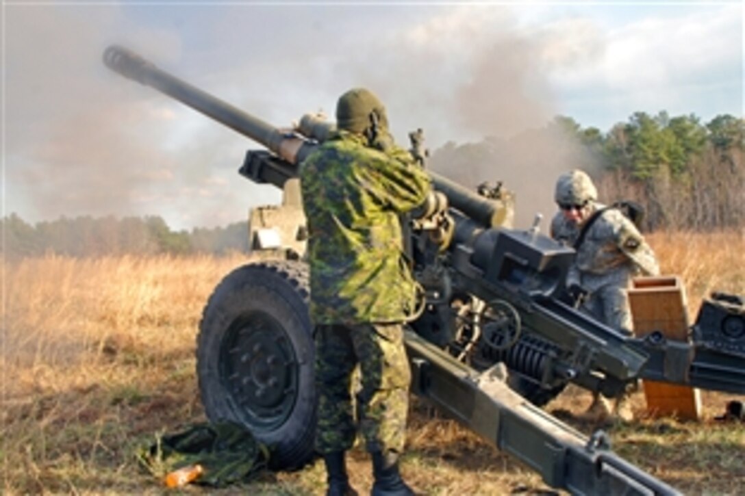 U.S. Army Spc. Christopher Rosario fires a C3 105mm howitzer during Exercise Southbound Trooper IX as Michael Habb, a bombardier from the Canadian 1st Field Artillery Regiment, 36 Canadian Brigade Group, observes on Fort Pickett, Va. Feb. 16, 2009. Rosario is assigned to the 55th Signal Company, Combat Camera.