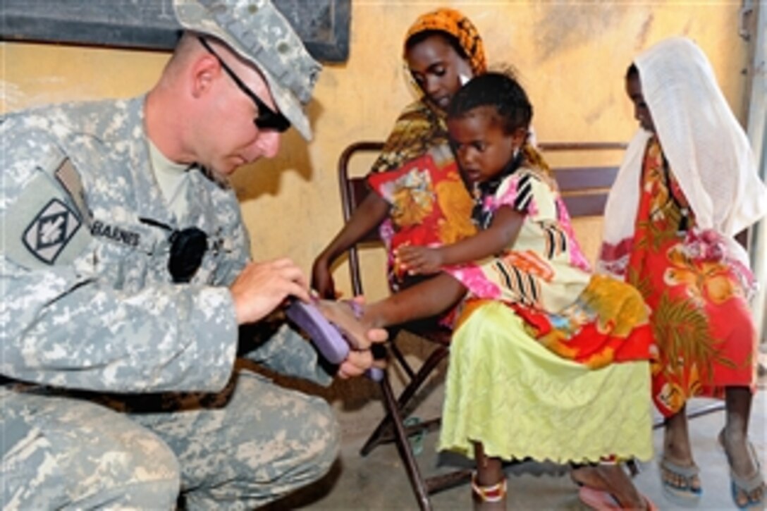 U.S. Army Staff Sgt. Cameron Barnes puts shoes on a child during a medical civil action program in the village of Milo, Ethiopia, Feb. 9, 2009. U.S. military personnel are providing medical assistance and services to villagers who would otherwise go without help.