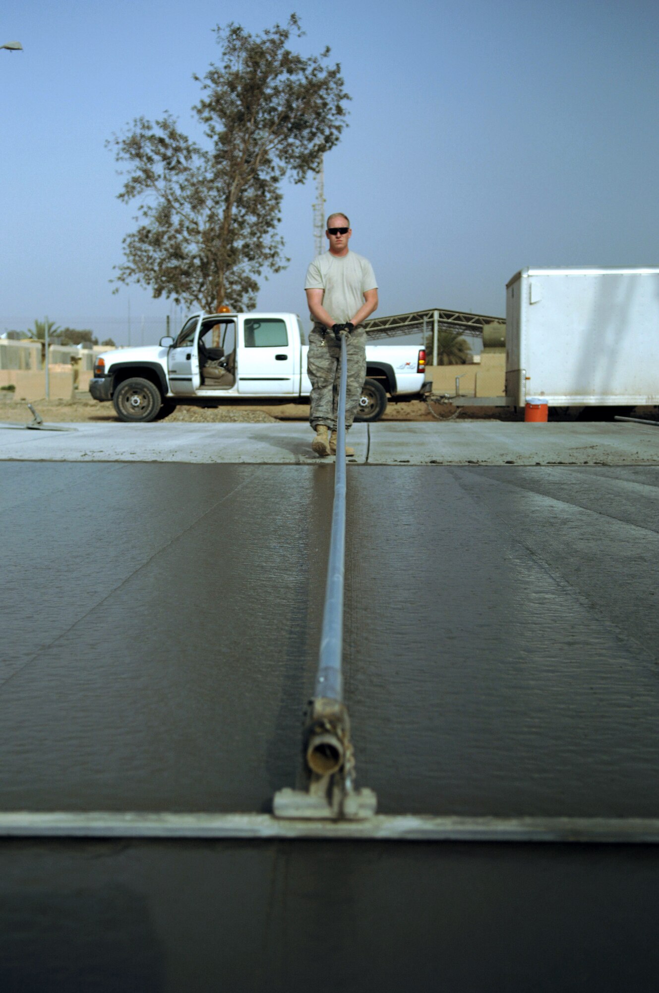 Tech. Sgt. Bryan Crane uses a cement-finishing tool called a bull float to even out the surface of a concrete pad Feb. 15 during a construction project at Joint Base Balad, Iraq. Sergeant Crane, a pavement and construction equipment operator with the 332nd Expeditionary Civil Engineer Squadron, helped complete a 76-meter concrete pad. He is deployed from Grand Forks Air Force Base, N.D. (U.S. Air Force photo/Staff Sgt. Dilia Ayala) 