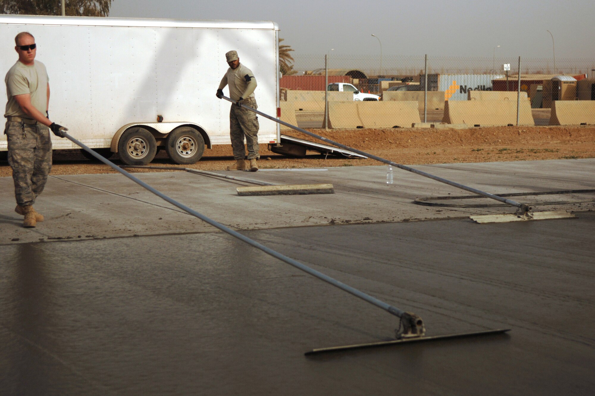 Tech. Sgt. Bryan Crane (left) and Staff Sgt. Derek McDonald use cement-finishing tools to even out the surface of a concrete pad Feb. 15 during a construction project at Joint Base Balad, Iraq.  The NCOs, pavement and construction equipment operators with the 332nd Expeditionary Civil Engineer Squadron, helped complete a 76-meter concrete pad. Sergeant Crane is deployed from Grand Forks Air Force Base, N.D., and Sergeant McDonald is deployed from Andrews AFB, M.D. (U.S. Air Force photo/Staff Sgt. Dilia Ayala) 
