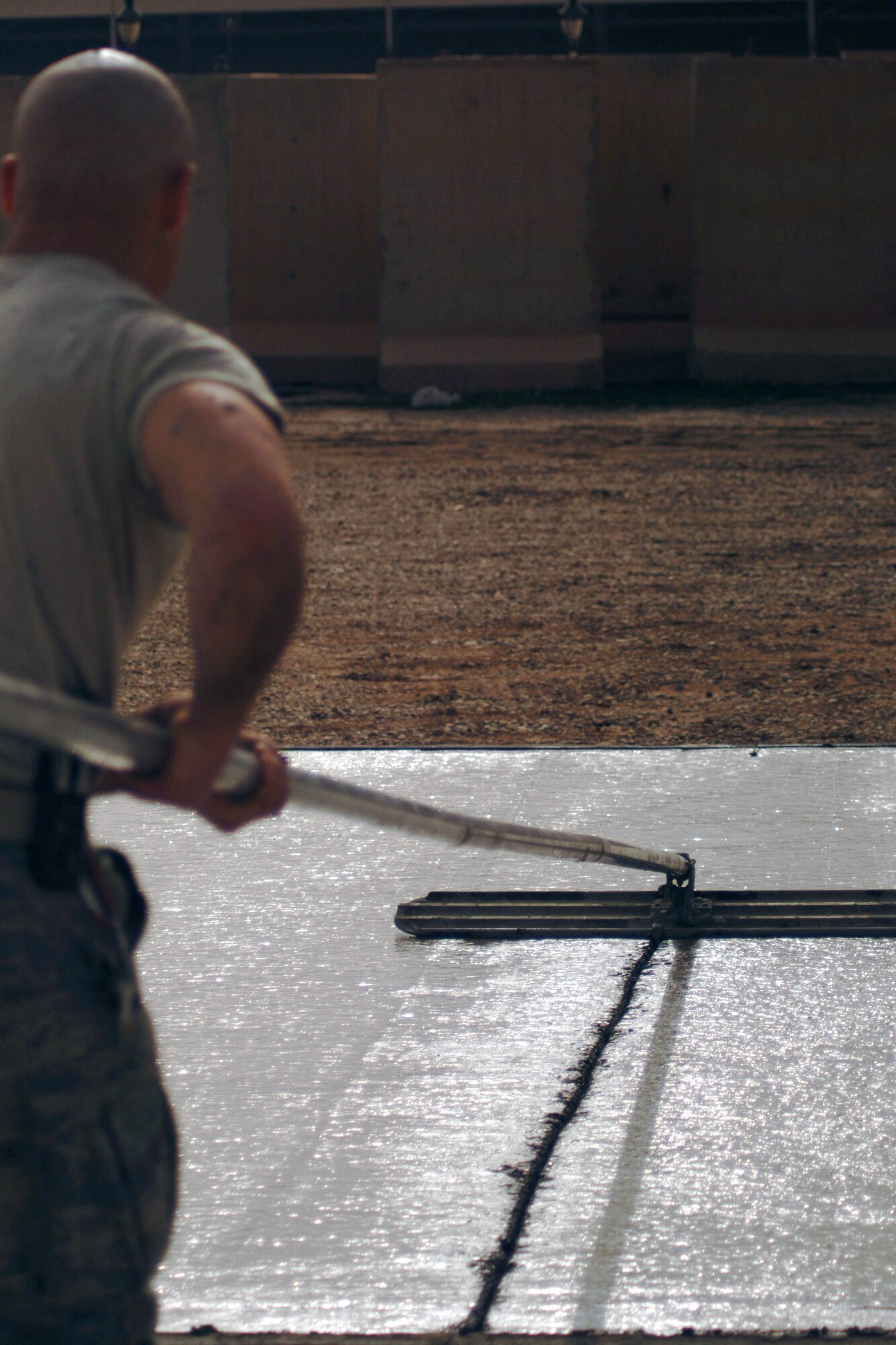 Staff Sgt. Jason Hopper uses a cement-finishing tool called a bull float Feb. 15 to even out the surface of a concrete pad during a construction project at Joint Base Balad, Iraq. He helped complete a 76-meter concrete pad. Sergeant Hopper, a native of Strongs, Mich., is a pavement and construction equipment operator with the 332nd Expeditionary Civil Engineer Squadron and is deployed from Elmendorf Air Force Base, Alaska. (U.S. Air Force photo/Staff Sgt. Dilia Ayala) 