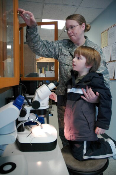 Staff Sgt. Laurie Kidwell, 341st Medical Operations Squadron NCO in charge of public health, pulls a spider from  a display case for her son David, 4 1/2, to look at under a microscope at the 341st Civil Engineer Squadron entomology office Feb. 17. The Kidwell's will soon leave for Wright-Patterson Air Force Base on a humanitarian reassignment so David can receive further treatment for autism. (U.S. Air Force photo/Senior Airman Dillon White)
