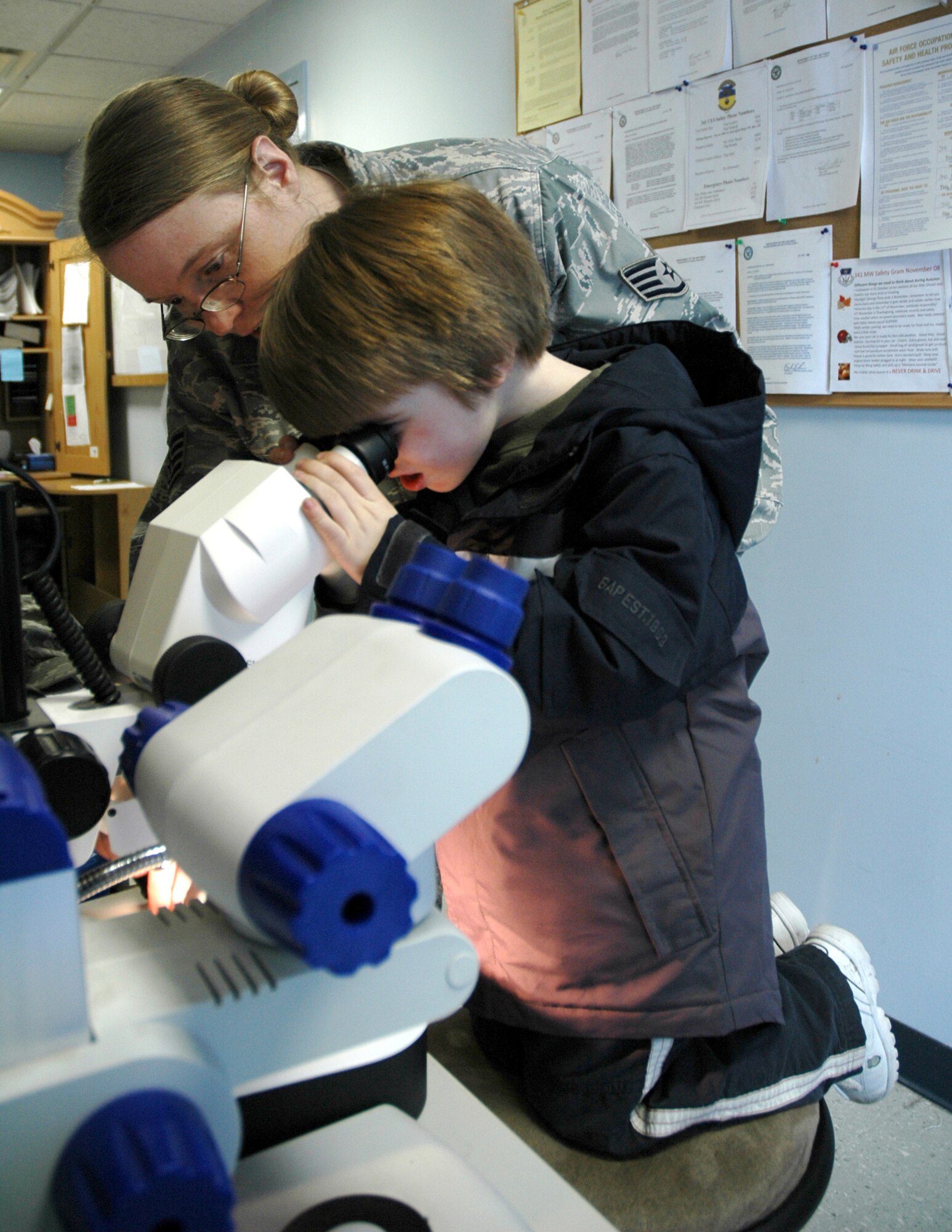 David, 4 1/2, looks at a spider under a microscope at the 341st Civil Engineer Squadron entomology office, while Staff Sgt. Laurie Kidwell, his mother, helps position the specimen. The Kidwell's will soon leave Malmstrom Air Force Base for Wright-Patterson AFB, Ohio, where David can receive further treatment for Autism. (U.S. Air Force photo/Senior Airman Dillon White) 