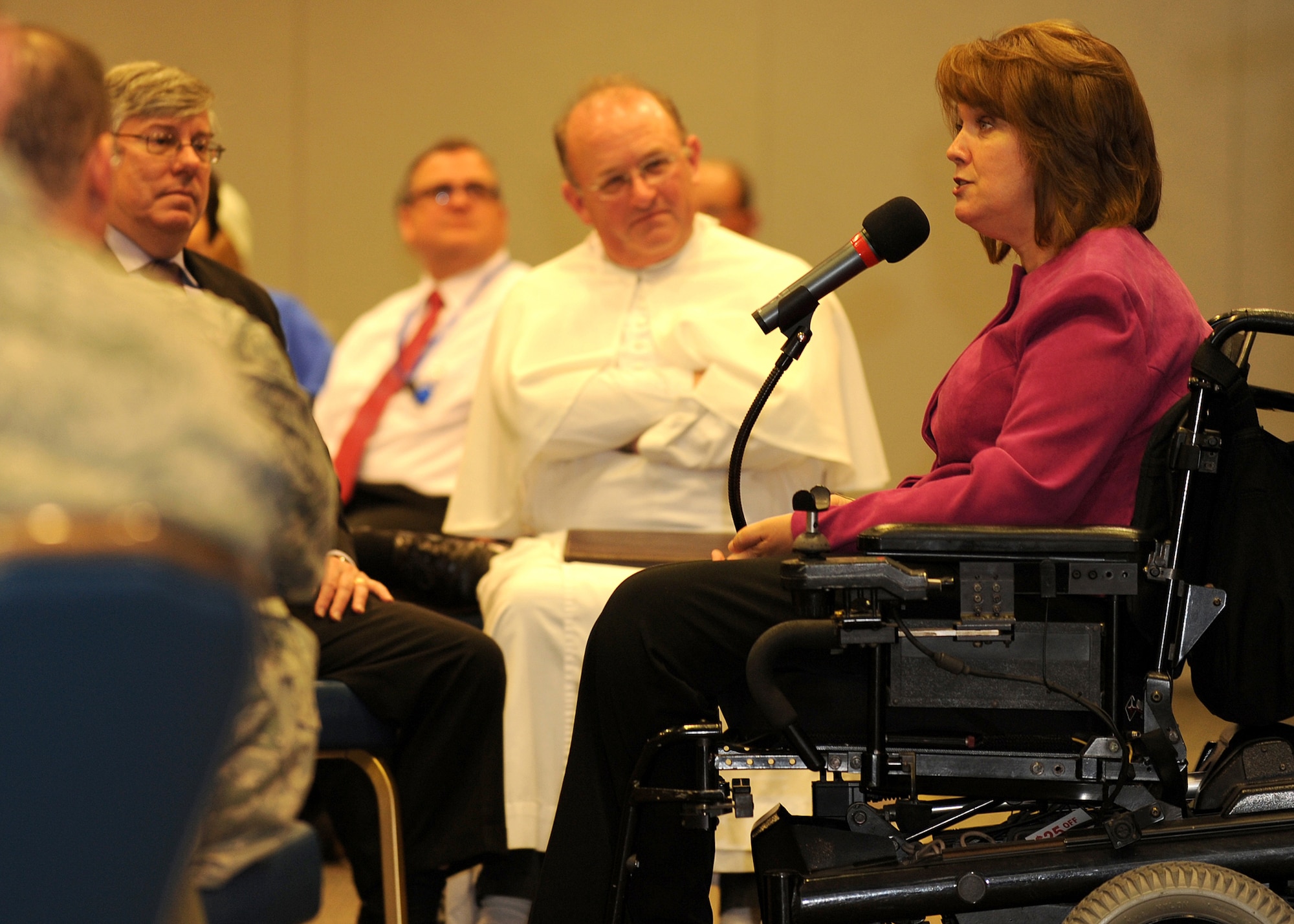 Reverend Martin Benzoni, Los Angeles AFB Auxiliary Catholic Priest, listens as keynote speaker Ms. Renée Bondi tells the audience of her amazing story of faith. Father Benzoni, a long-time friend of Ms. Bondi, met her 20 years ago while they were both involved in a program working with teenagers in San Juan Capistrano, Calif. (Photo by Stephen Schester)