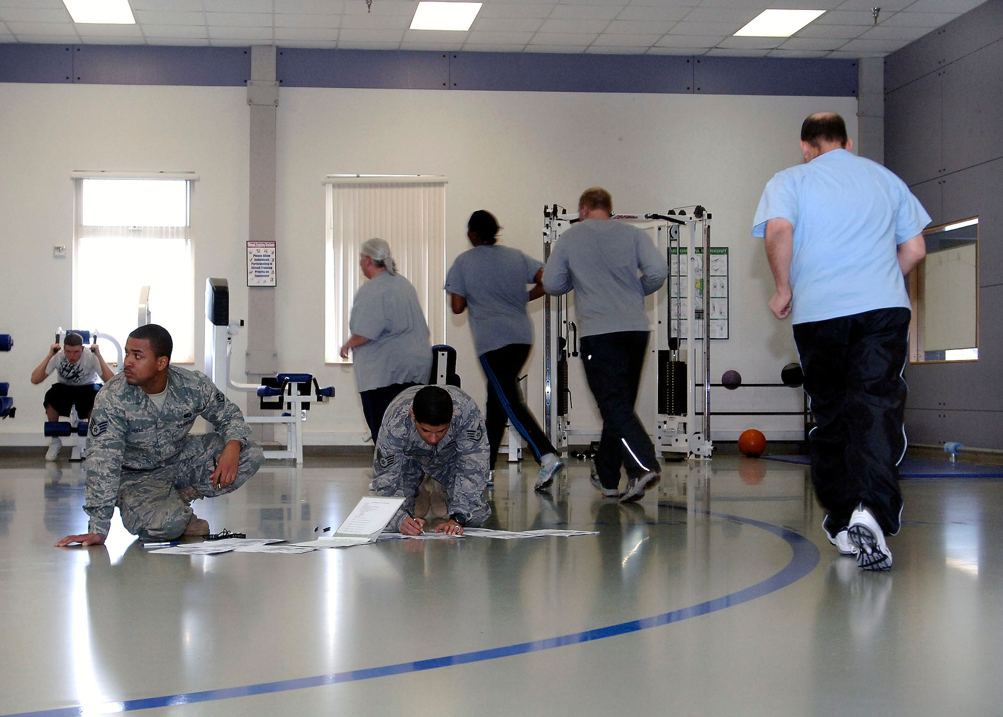 Staff Sgt. Steven Hall III, 92nd Force Support Squadron special events coordinator, and Staff Sgt. Ruban Garcia, 92nd FSS  fitness supervisor,  give encouragement and keep track of how many laps each person is running during the initial Physical Training test conducted in the first week of Monster Boot Camp.  For six weeks participants in the program will progressively improve their physical fitness through a plethora of total body workouts conducted by certified personal trainers at the fitness center. (U.S. Air Force photo / Airman 1st Class Melissa L. Barnett)
