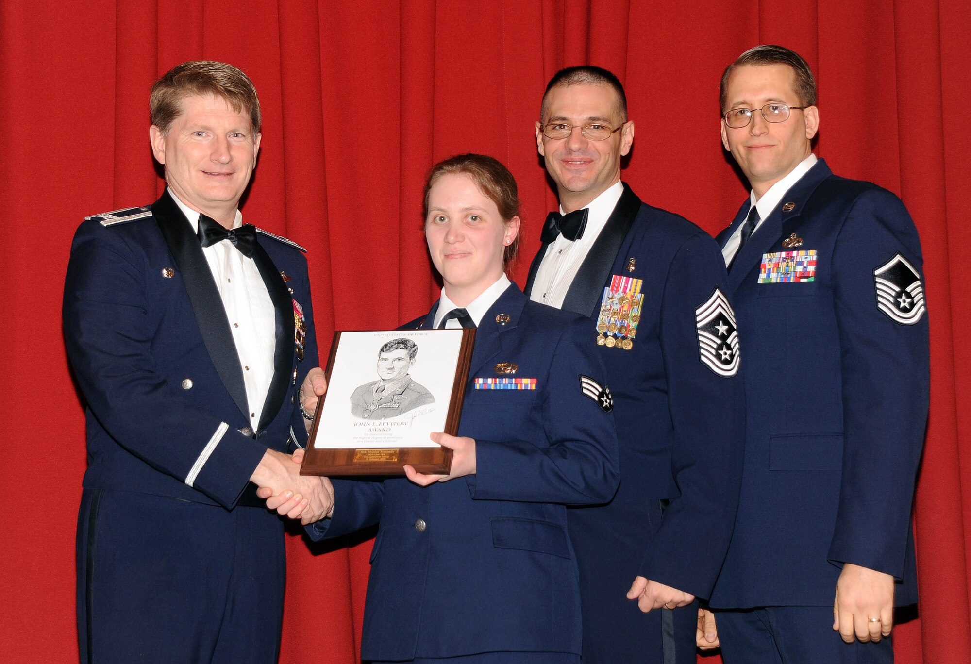 Col. Robert Thomas, 92nd Air Refueling Wing commander, and Command Chief Master Sgt. David Nordel present Senior Airman Monica Symonds, 92nd Operations Group, with the John Levitow Award during the Airman Leadership School graduation Feb. 12, while Master Sgt. Lester Gaither, 92nd Maintenance Squadron, looks on. The prestigious Levitow award is the highest professional military education award given in enlisted PME classes, indicating excellence in academics, leadership and peer standing. (U.S. Air Force photo / Staff Sgt. JT May III)