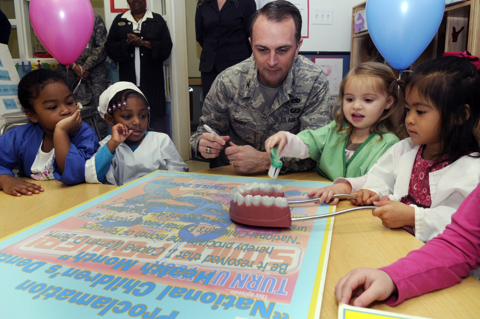 Col. Warren Berry, center, 78th Air Base Wing commander, visited with children at the Child Development Center East to sign a proclamation for  National Children's Dental Health Month  Feb. 10. The children dressed in dental scrubs for the event. U. S. Air Force photo by Sue Sapp