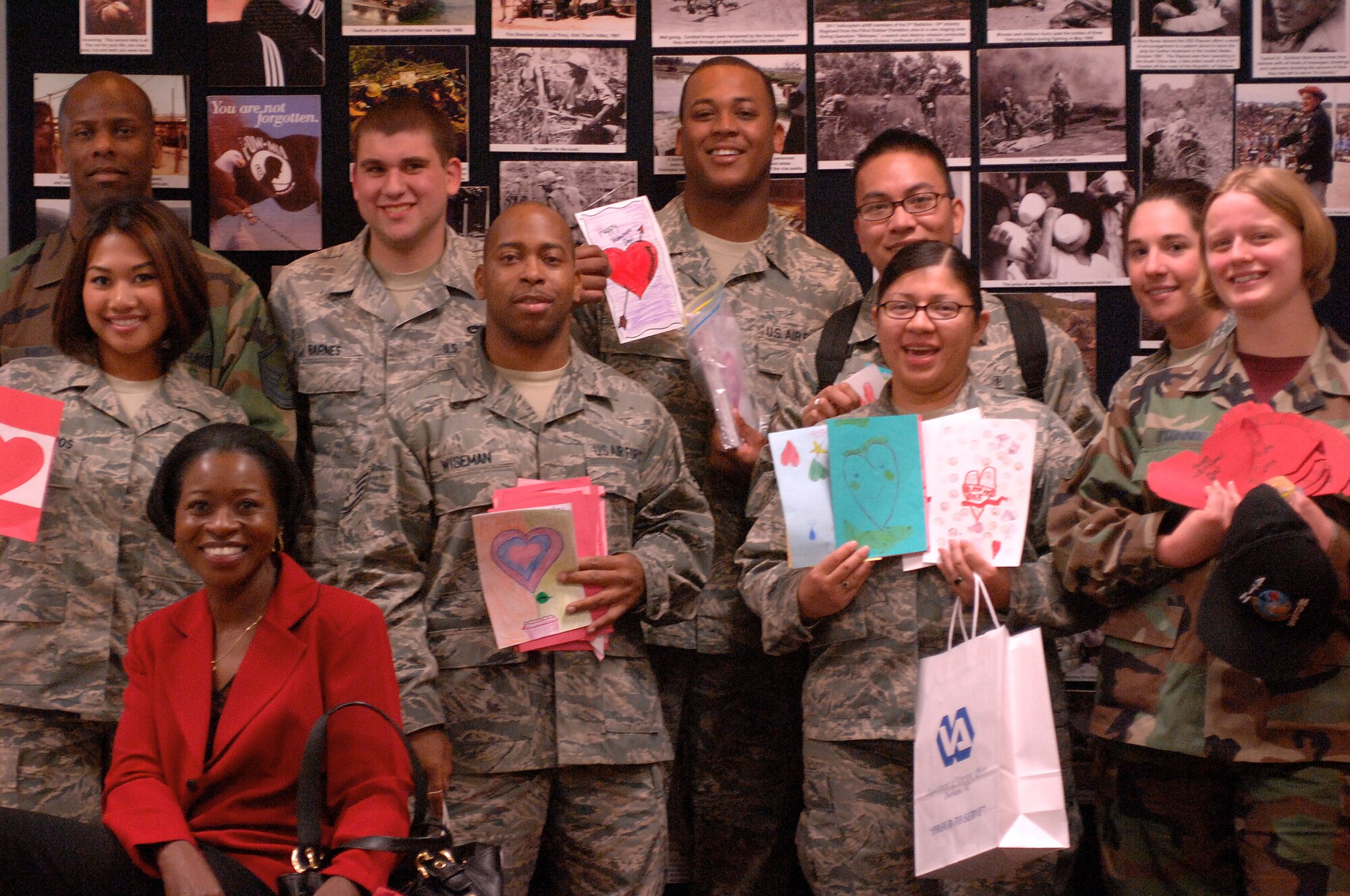 Participants of the annual Valentines for Vets visit to Durham Veterans Administration Medical Center stand in front of a collage with photos of the Korean War Feb. 13, 2009. Valentines for Vets is a volunteer event where Airmen and civilians from the base bring toiletries and valentines cards made by local children to the hospital. (U.S. Air Force photo by Airman 1st Class Marissa Tucker)