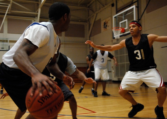 Averion Williamson dribbles the ball as LaQuinn Mims attempts to block him during the intramural basketball game at the Fitness and Sports Center here Feb. 18. FSS dominated LRS 2 72-25. Williamson is with the 437th Logistics Readiness Squadron and Mims is with the 437th Force Support Squadron. (U.S. Air Force photo/Senior Airman Katie Gieratz)