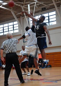 Clinton Coleman and Donald Speller reach for the ball at the beginning of the intramural basketball game at the Fitness and Sports Center here Feb. 18. FSS dominated LRS 2 72-25. Coleman is with the 437th Force Support Squadron and Speller is with the 437th Logistics Readiness Squadron. (U.S. Air Force photo/Senior Airman Katie Gieratz) 