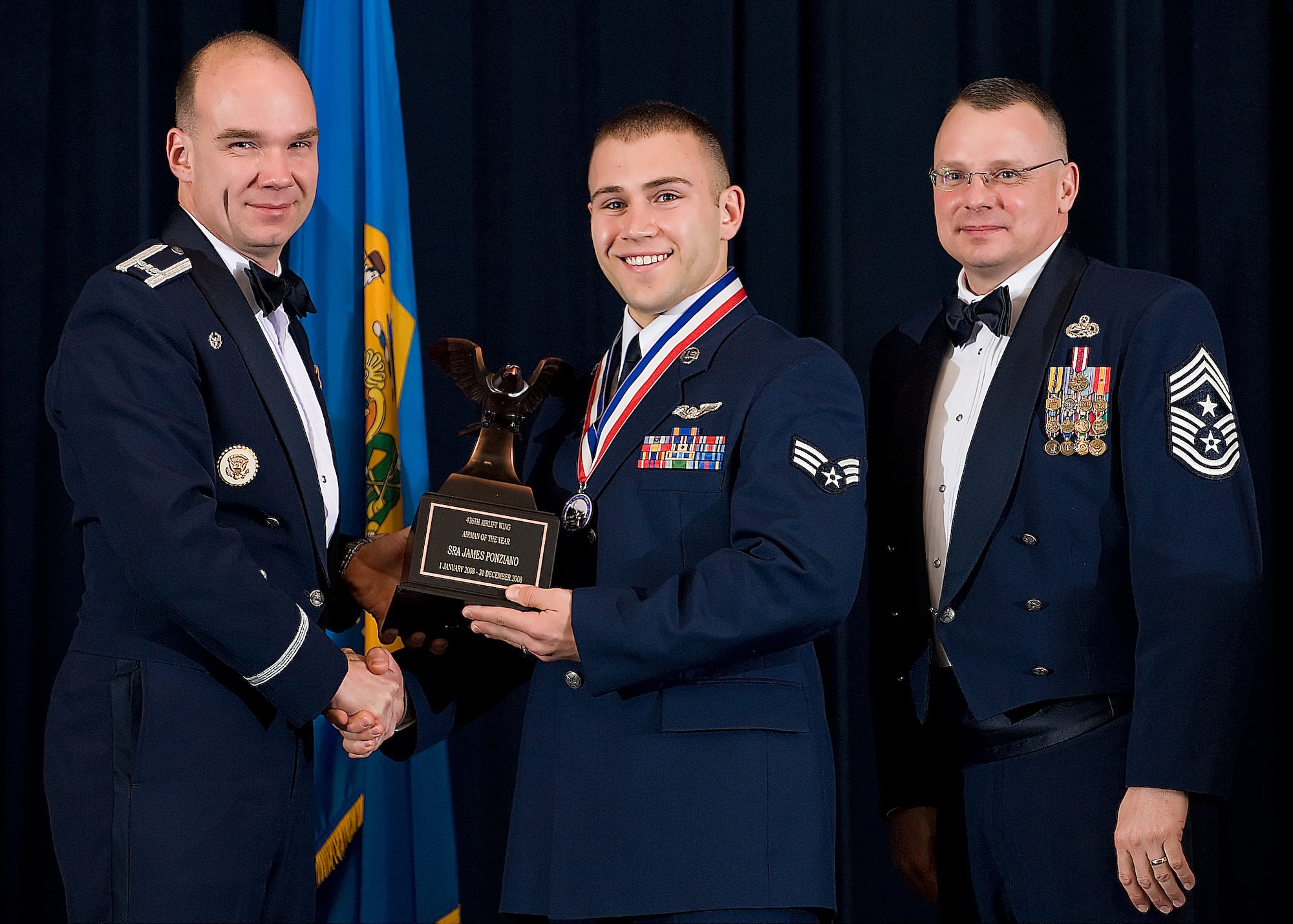 (Left) Col. Manson Morris, 436th Airlift Wing commander, and Chief Master Sgt. John Wood, 436th AW command chief, present Senior Airman James Ponziano, 3rd Airlift Squadron, with the award for Airman of the Year during the Annual Awards ceremony Feb. 13.  (U.S. Air Force photo/Roland Balik)