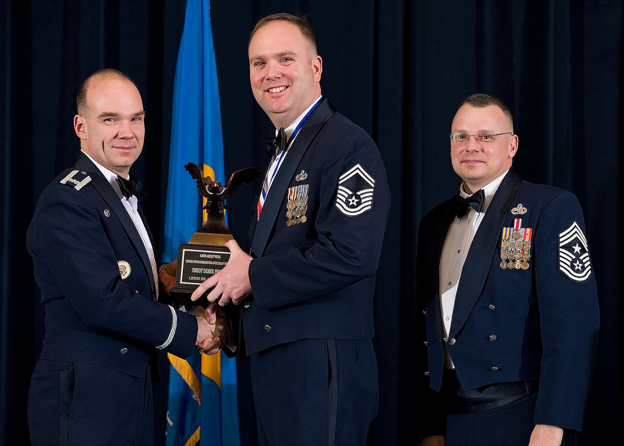 (Left) Col. Manson Morris, 436th Airlift Wing commander, and Chief Master Sgt. John Wood, 436th AW command chief, present Senior Master Sgt. Derek Finney, 436th Security Forces Squadron, with the award for Senior Non-commissioned Officer of the Year during the Annual Awards ceremony Feb. 13.  (U.S. Air Force photo/Roland Balik)