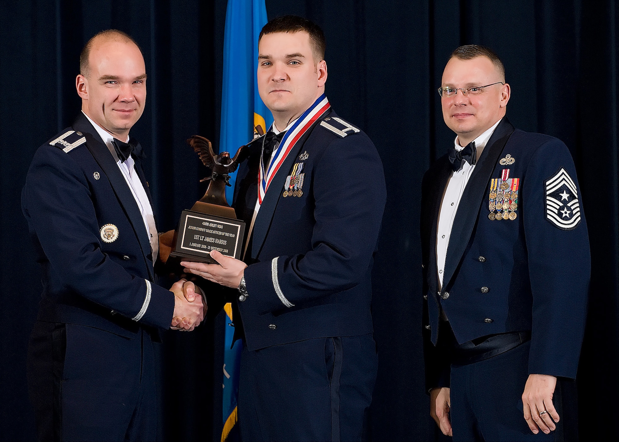 (Left) Col. Manson Morris, 436th Airlift Wing commander, and Chief Master Sgt. John Wood, 436th AW command chief, present 1st Lt. James Harris, 436th Aircraft Maintenance Squadron, with the award for Junior Company Grade Officer of the Year during the Annual Awards ceremony Feb. 13.  (U.S. Air Force photo/Roland Balik)